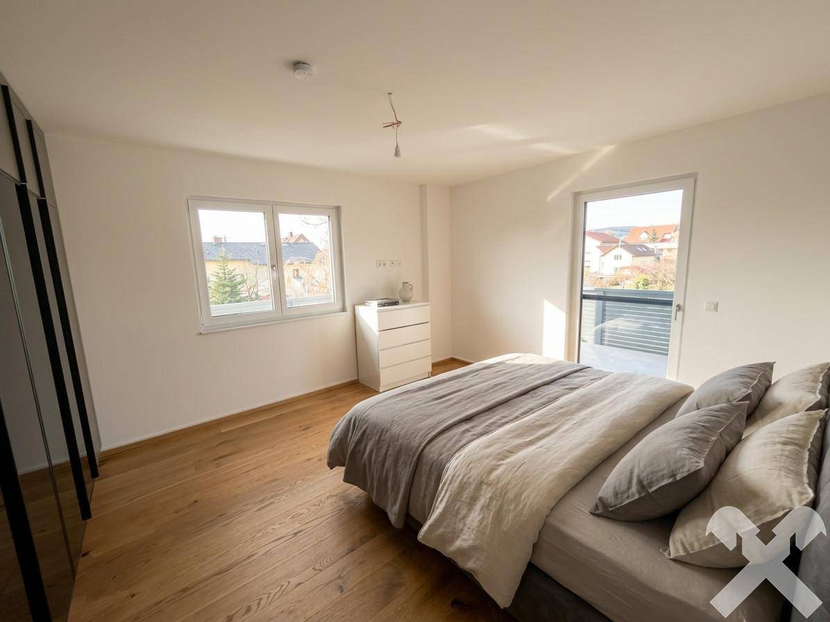 Helles Schlafzimmer mit Holzboden, großem Fenster und Zugang zum Balkon.