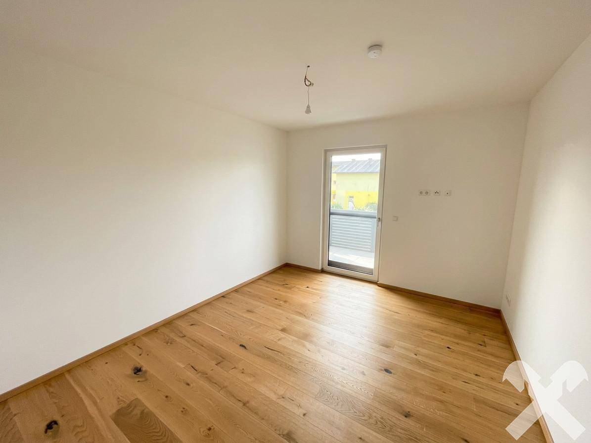 Leeres Zimmer mit Holzboden und Zugang zu einem Außenbereich, ideal als Schlaf- oder Gästezimmer.