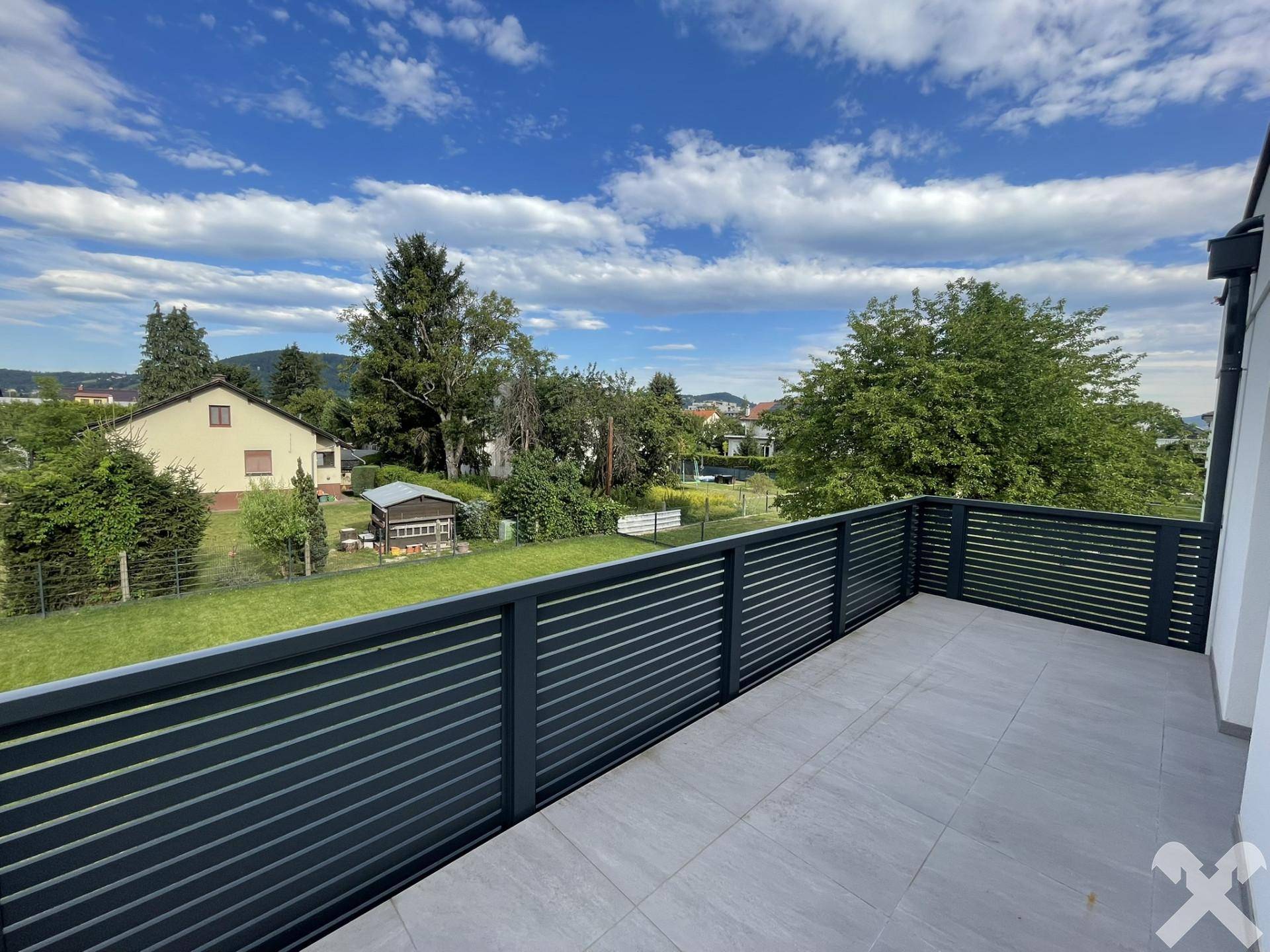 Großer Balkon mit modernen Geländern und weitem Blick ins Grüne und die Umgebung.