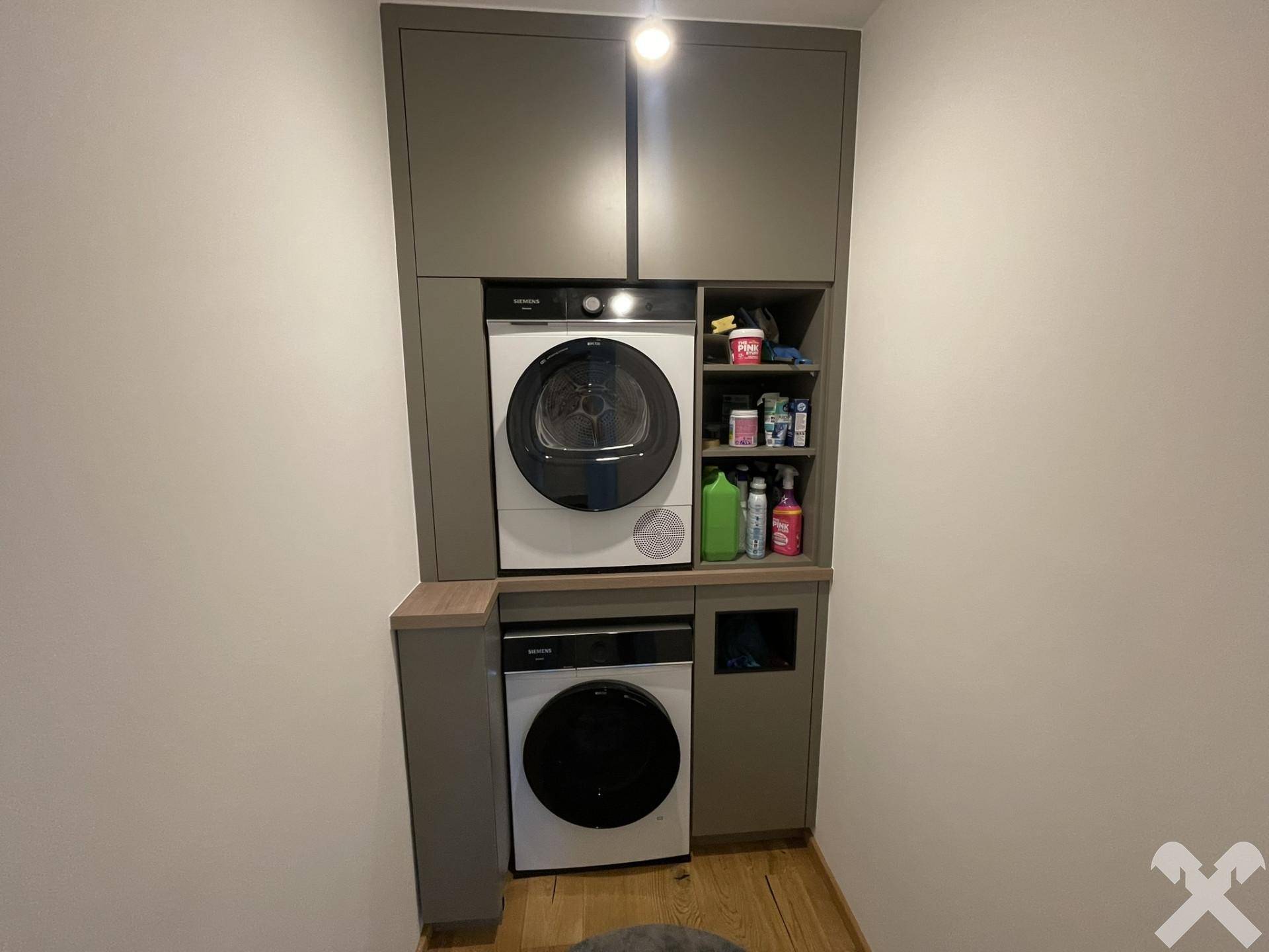 Praktischer Hauswirtschaftsraum mit Waschmaschine, Trockner und integrierten Schränken.