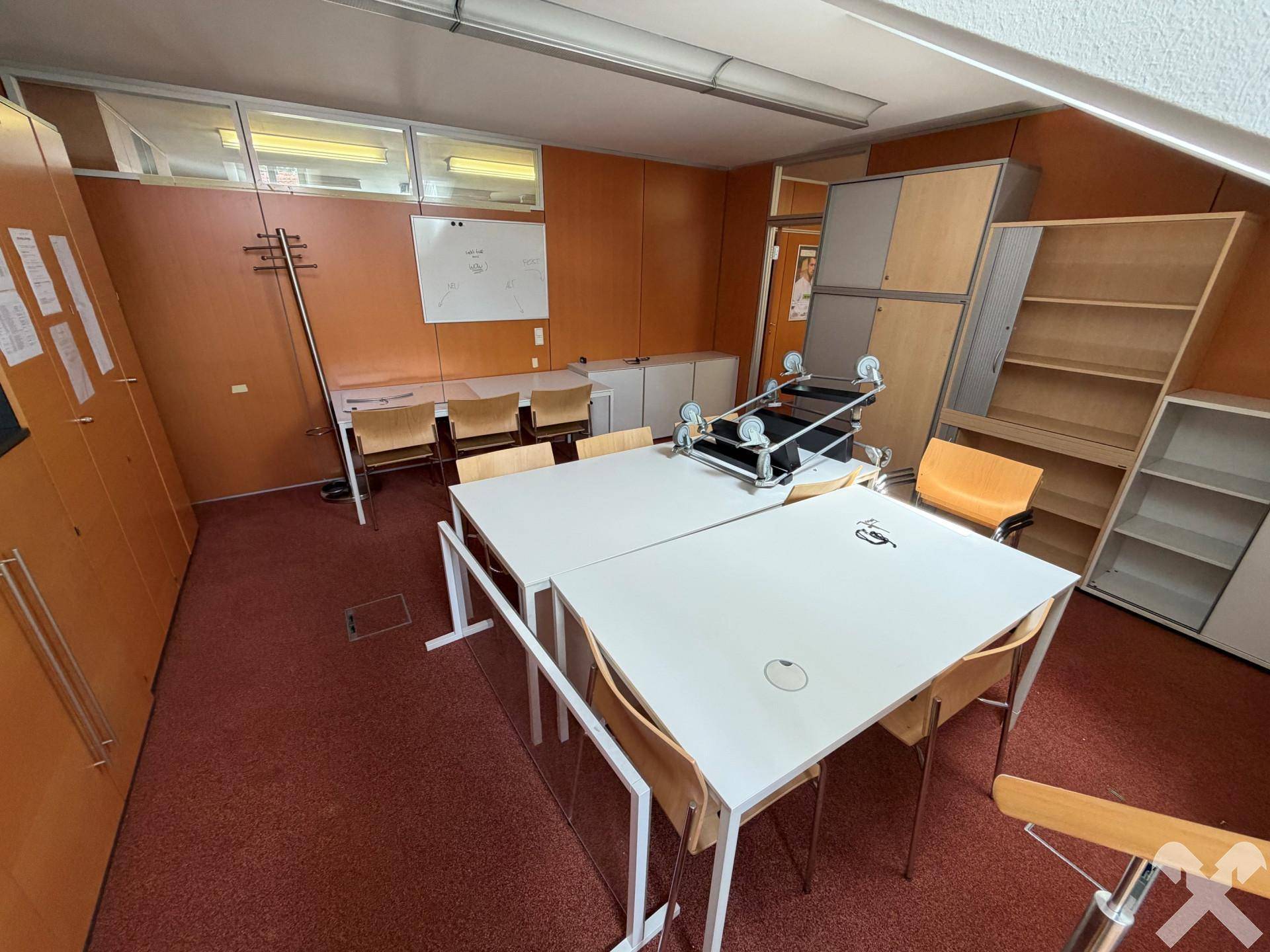 Büro oder Arbeitsraum mit Schränken, Tischen und einem Whiteboard, ideal für Teamarbeit.