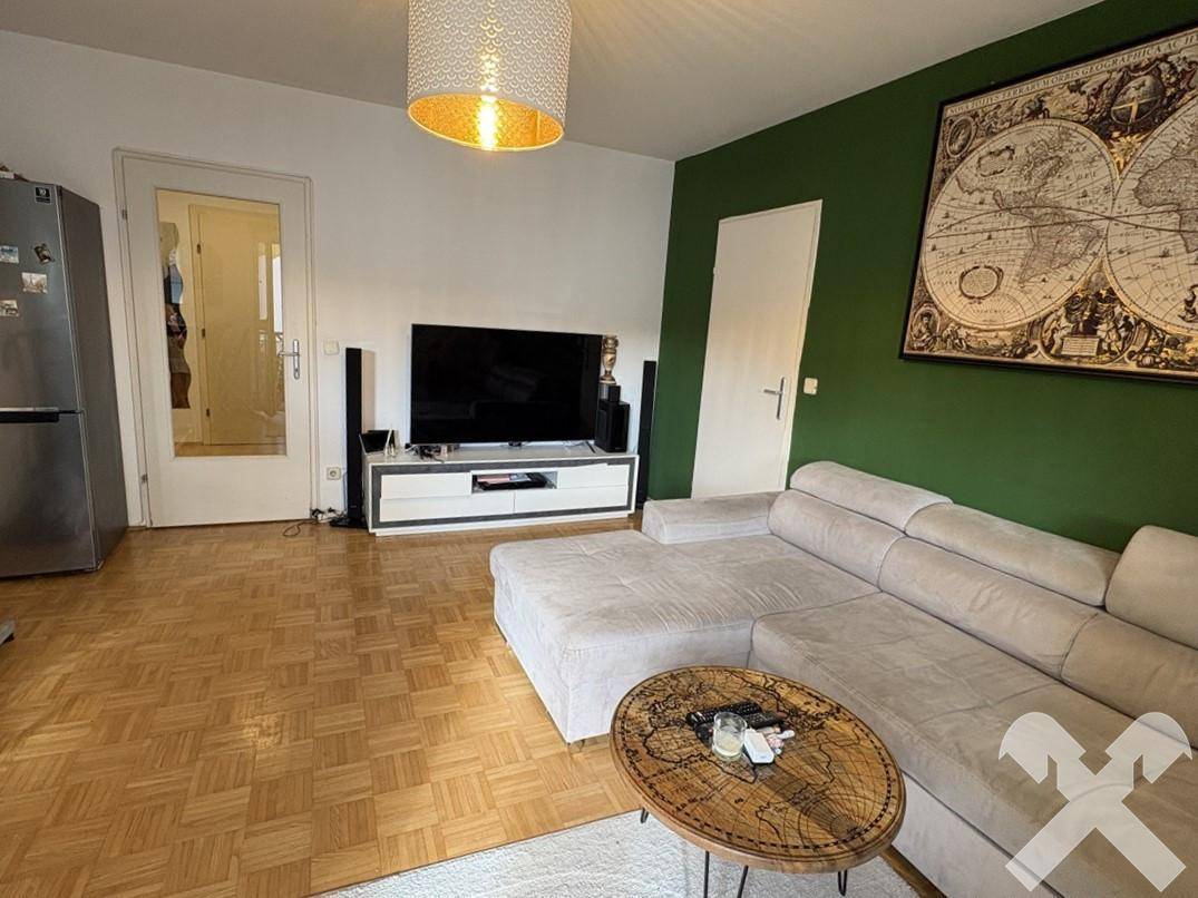 Gemütliches Wohnzimmer mit Ecksofa, Couchtisch und einem Weltkartenbild an der grünen Akzentwand.