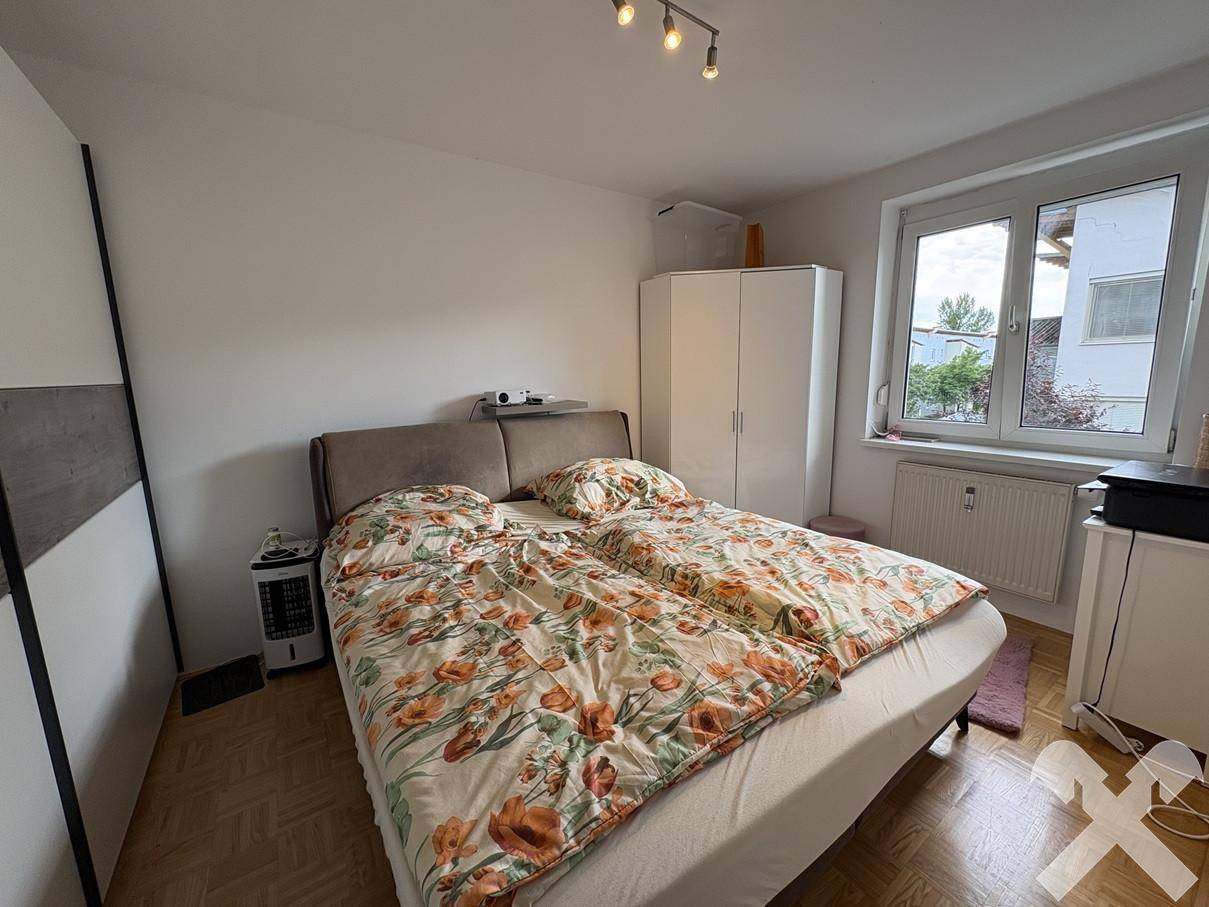 Schlafzimmer mit Doppelbett, Kleiderschrank und Fenster mit Blick ins Grüne, hell und freundlich.