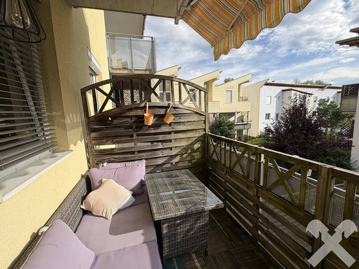Möblierter Balkon mit Markise und Blick auf die umliegenden Gebäude, ideal zum Entspannen.