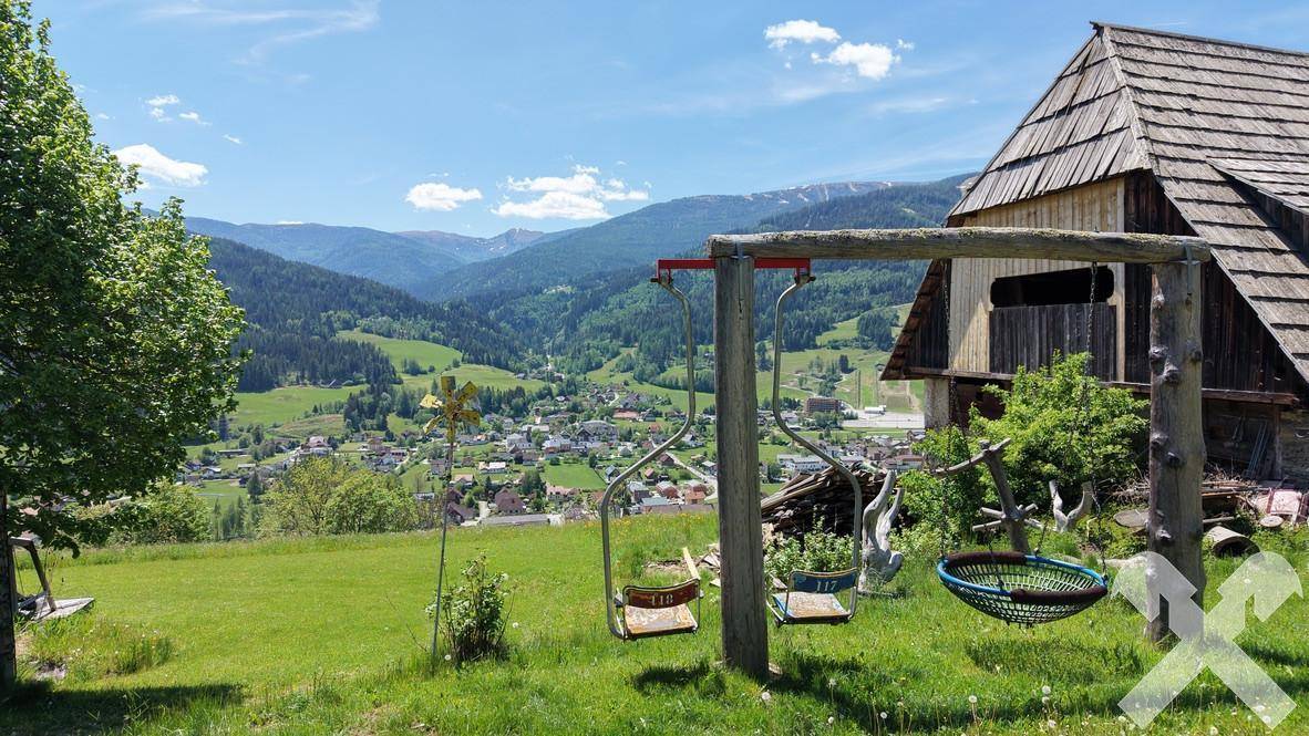 Kinderschaukeln mit weitem Blick über ein grünes Tal und die umliegende Berglandschaft.