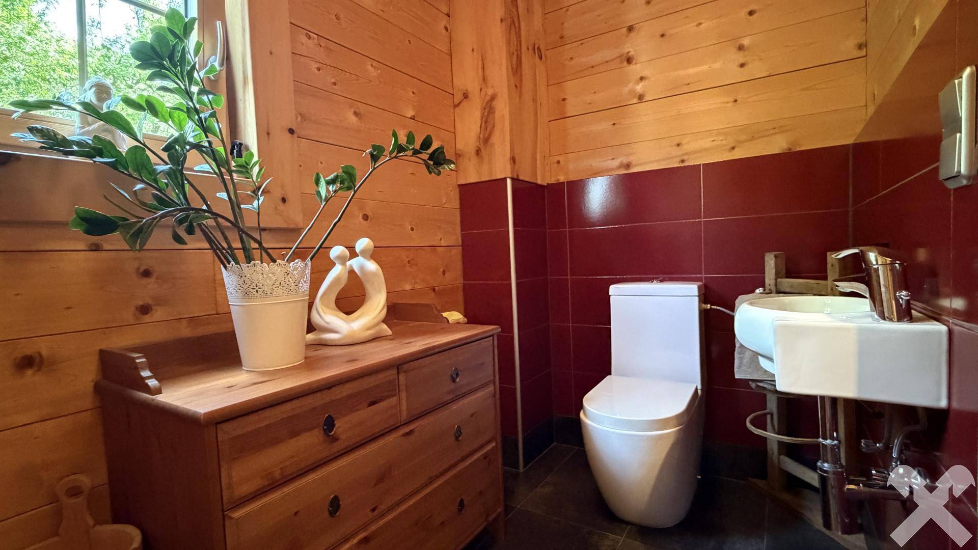 Kleines Gäste-WC mit Holzvertäfelung, rotem Fliesenspiegel und Fenster.