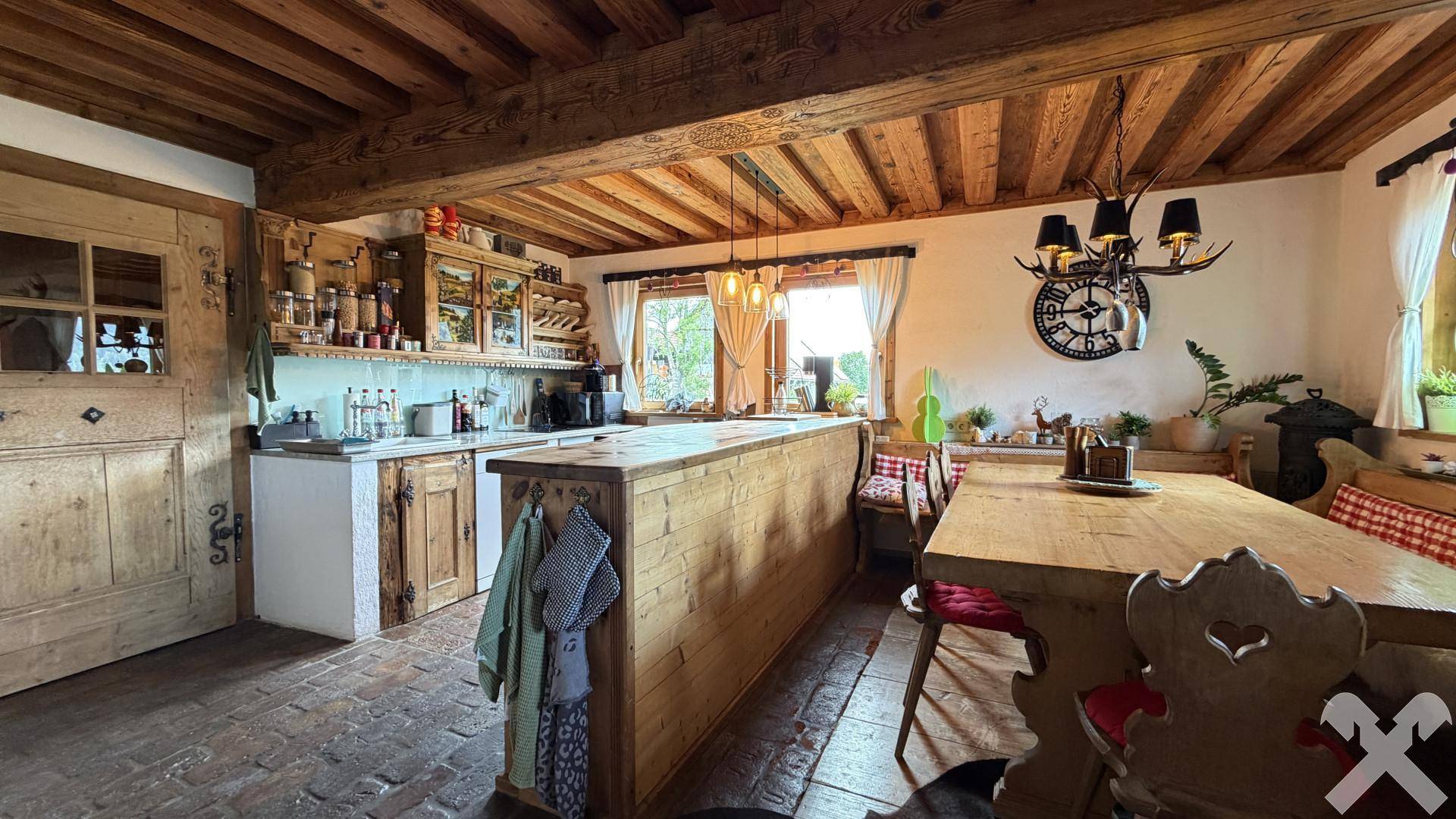 Rustikale Wohnküche mit Holzbalkendecke, Kücheninsel und traditionellem Essbereich.