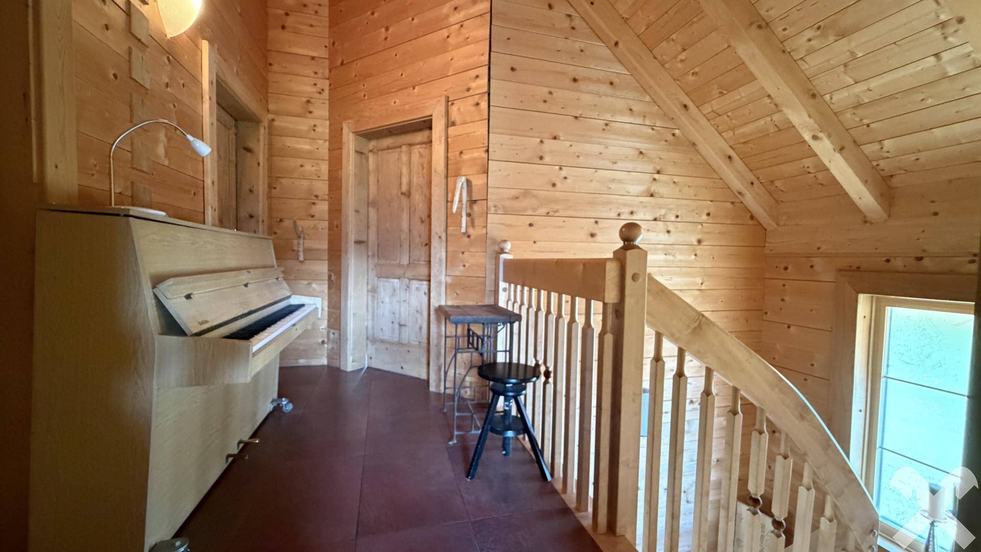 Heller Flur mit Holzvertäfelung, Treppe und einem Klavier.
