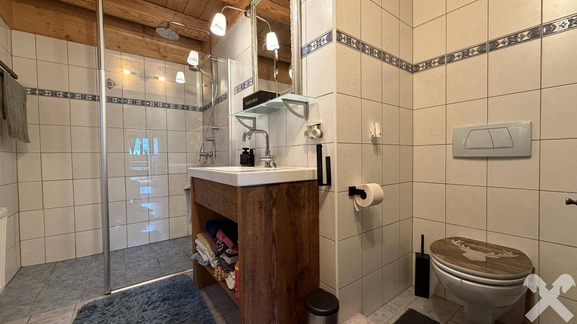 Rustikales Badezimmer mit Holzbalkendecke, begehbarer Dusche und einem Waschtisch aus Holz.