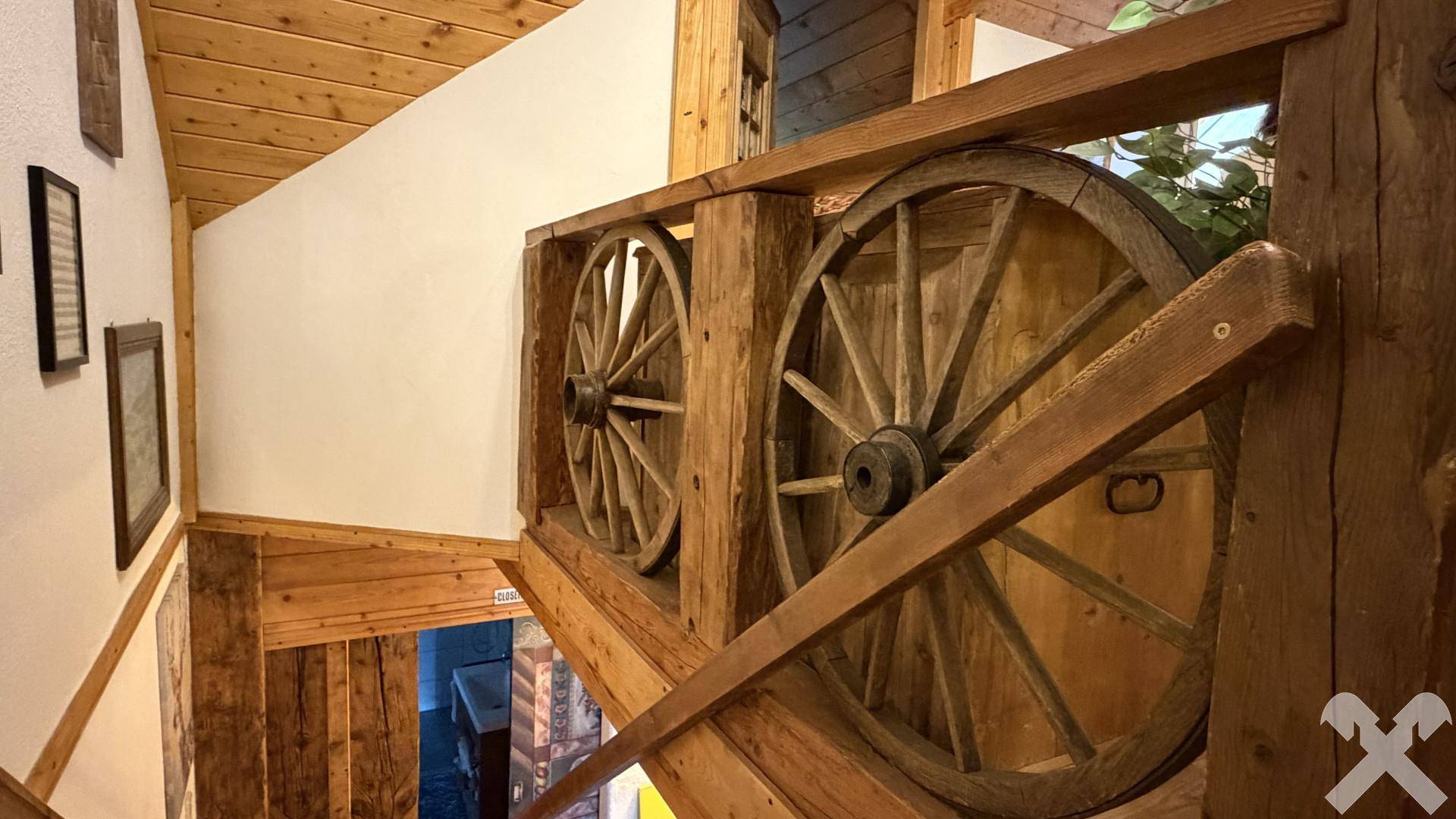 Einzigartiger Treppenaufgang mit Holzbalken und dekorativen Wagenrädern als Geländer im Landhausstil.
