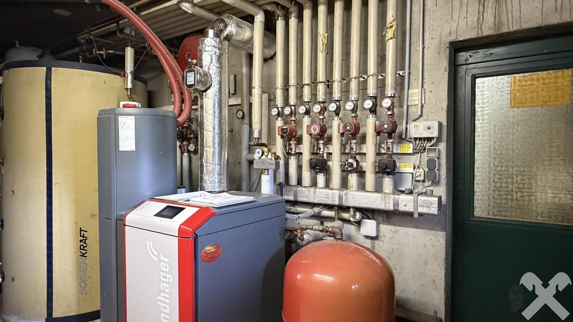Funktionaler Heizungsraum mit modernen Heizkesseln, Warmwasserspeichern und sichtbaren Rohrleitungen.