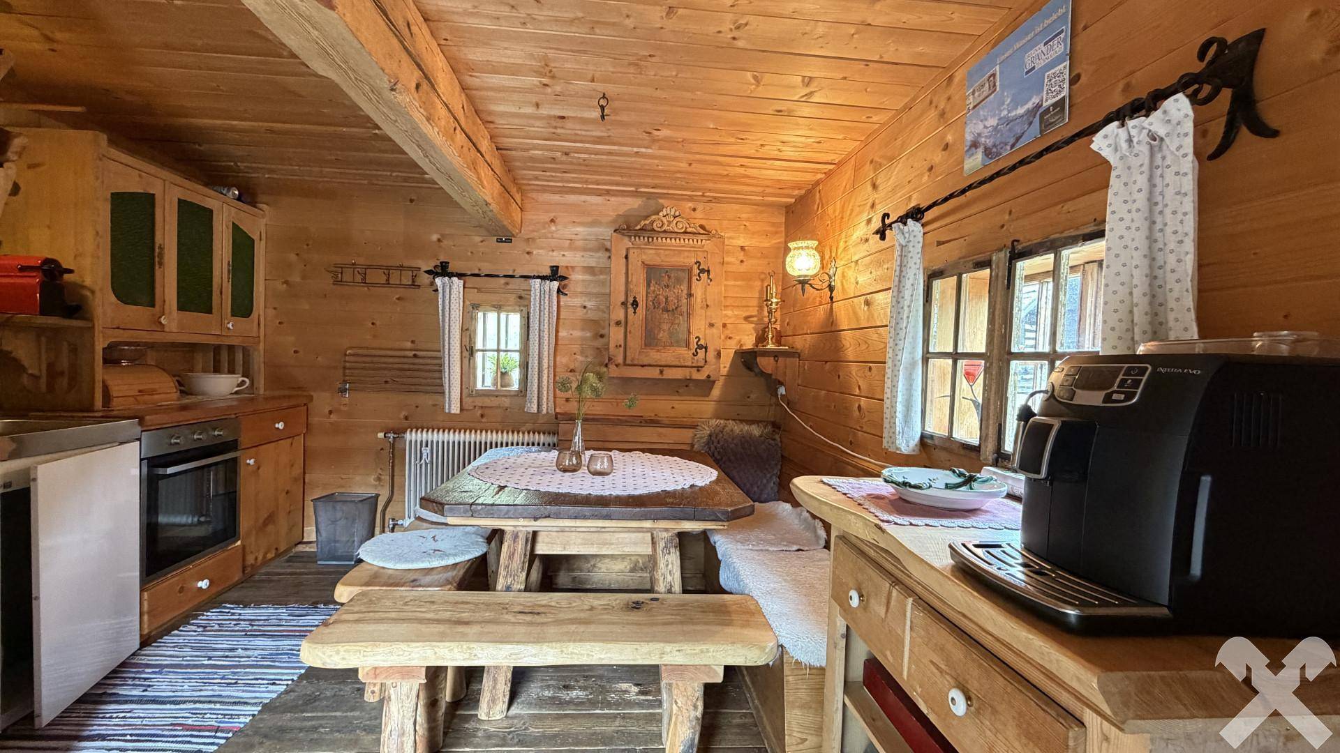 Rustikale Wohnküche mit Holztäfelung, einem massiven Holztisch und integrierten Küchengeräten.