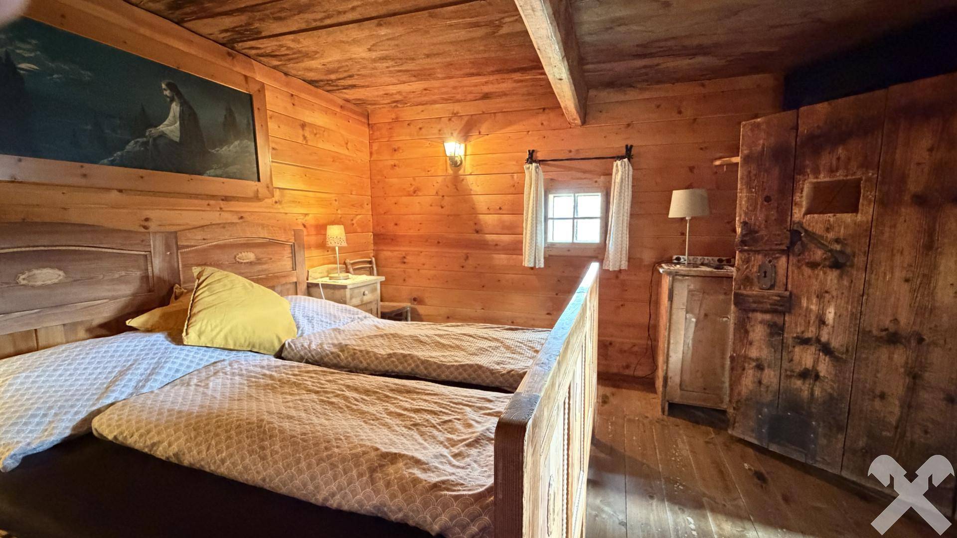 Gemütliches Schlafzimmer mit Holztäfelung, zwei Einzelbetten und rustikalen Holzmöbeln.