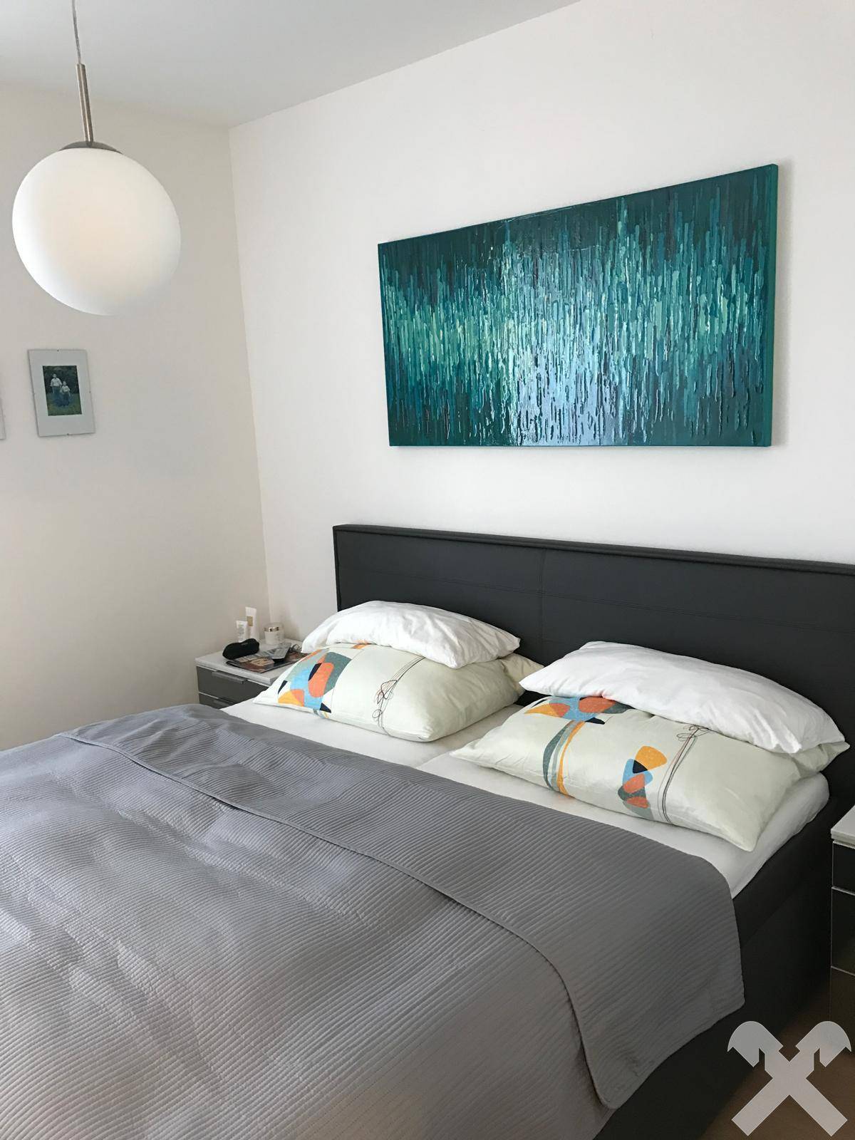 Schlafzimmer mit großem Doppelbett, Nachttischen und einem modernen Kunstwerk an der Wand.