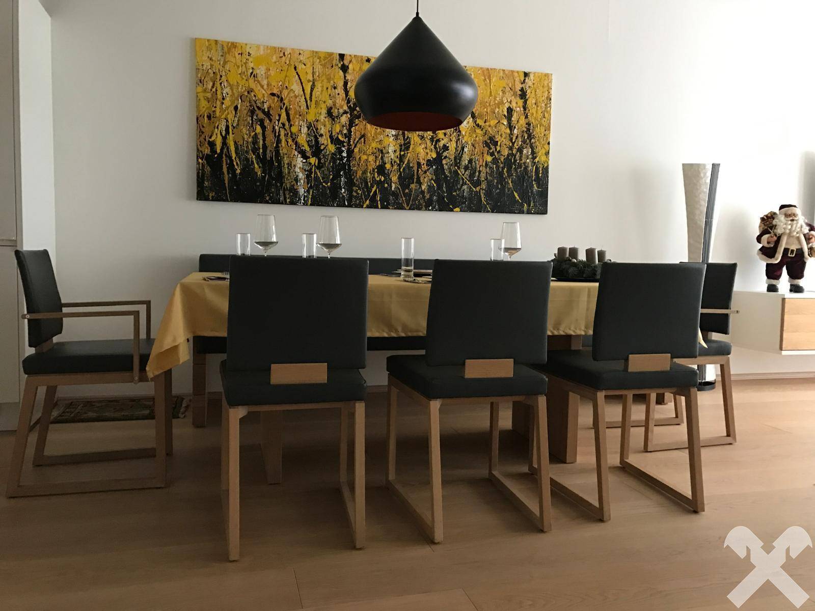 Eleganter Essbereich mit großem Holztisch, modernen Stühlen und einem auffälligen Kunstwerk.