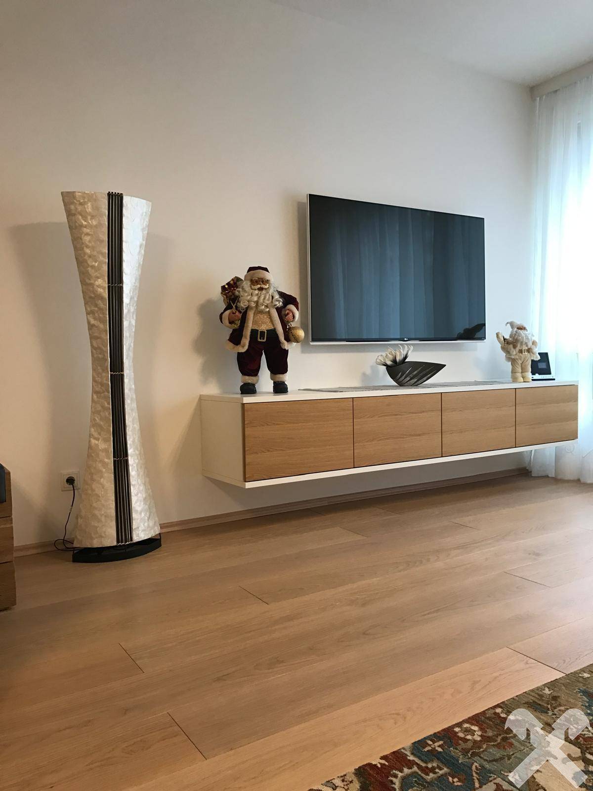 Moderner Wohnbereich mit wandmontiertem Fernseher und schwebendem Sideboard auf Holzparkett.