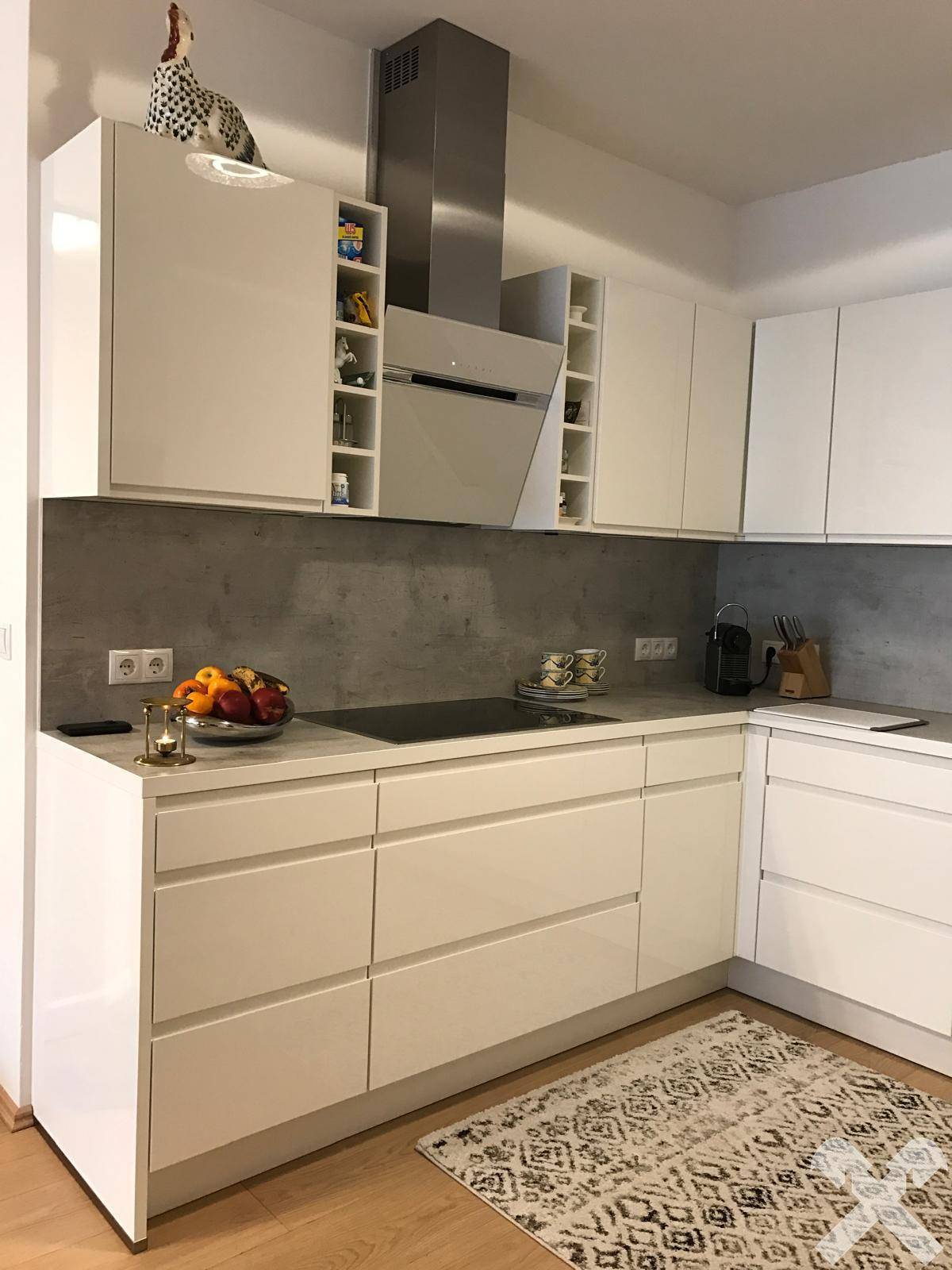 Helle, moderne Küche mit weißen Schränken, Induktionskochfeld und Dunstabzugshaube.
