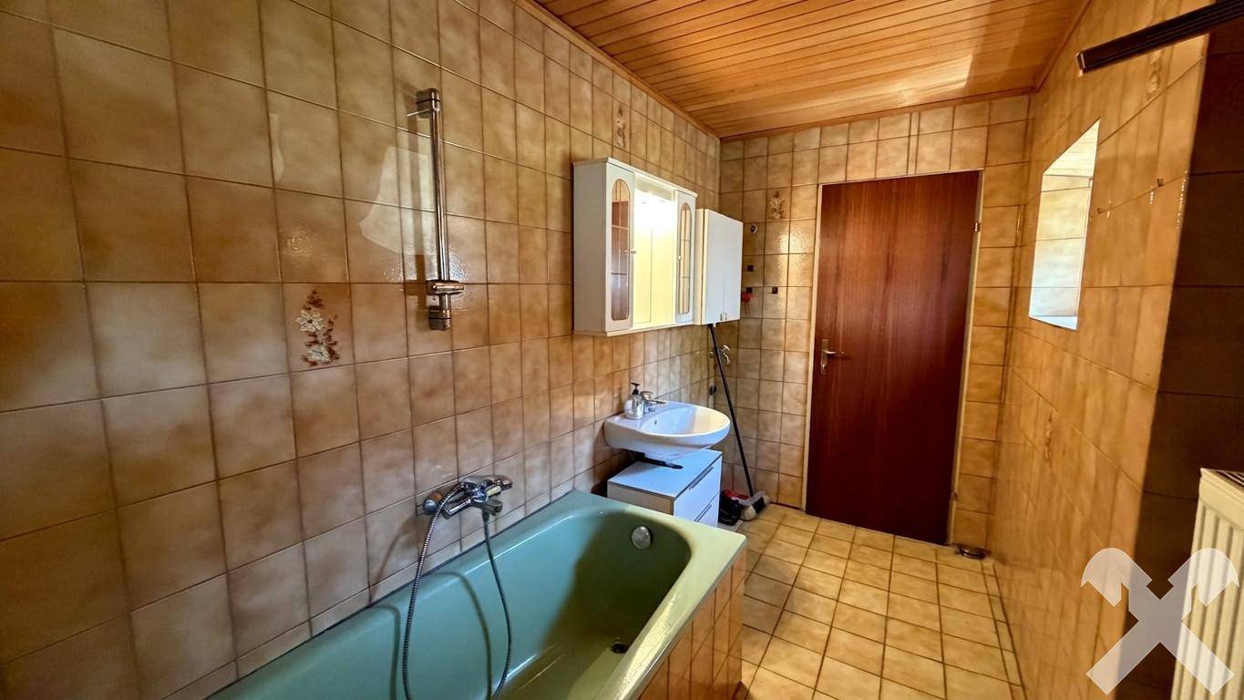 Badezimmer im Stil der 80er Jahre mit grüner Badewanne, braunen Fliesen und Holzdecke.