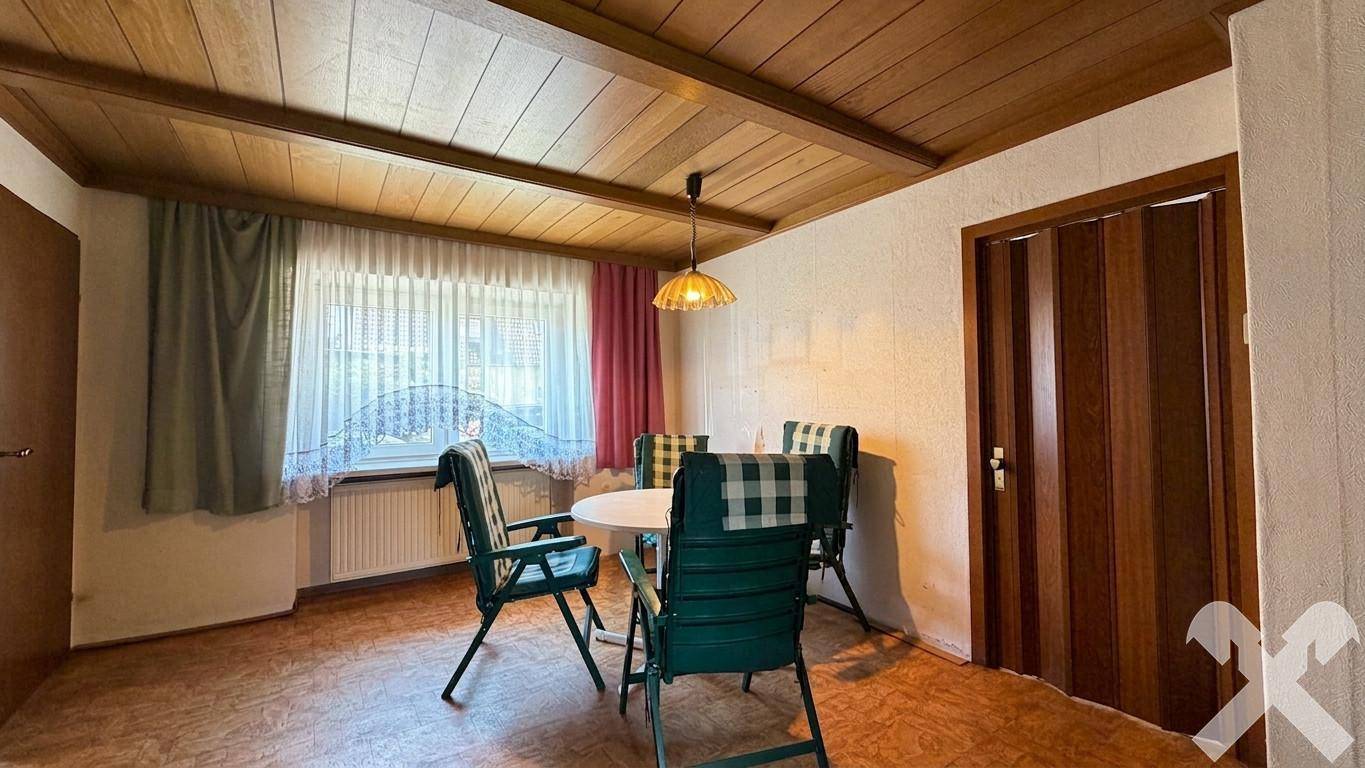 Gemütlicher Essbereich mit Holzdecke, karierten Stühlen und Blick nach draußen.