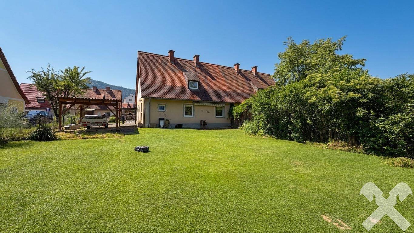 Großer, gepflegter Garten mit Rasenfläche, Hecke und Blick auf das Haus.