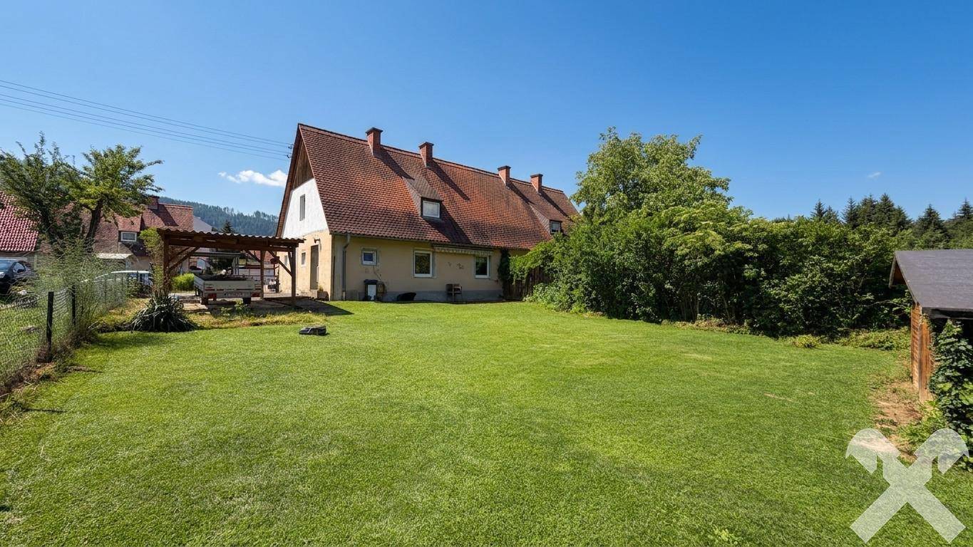 Weitläufiger Gartenbereich mit Rasen, Bäumen und Blick auf die ländliche Umgebung.