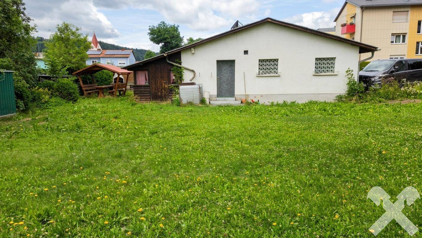 Haus mit großer Rasenfläche im Vordergrund und einem Holzpavillon mit Grillplatz im Garten.