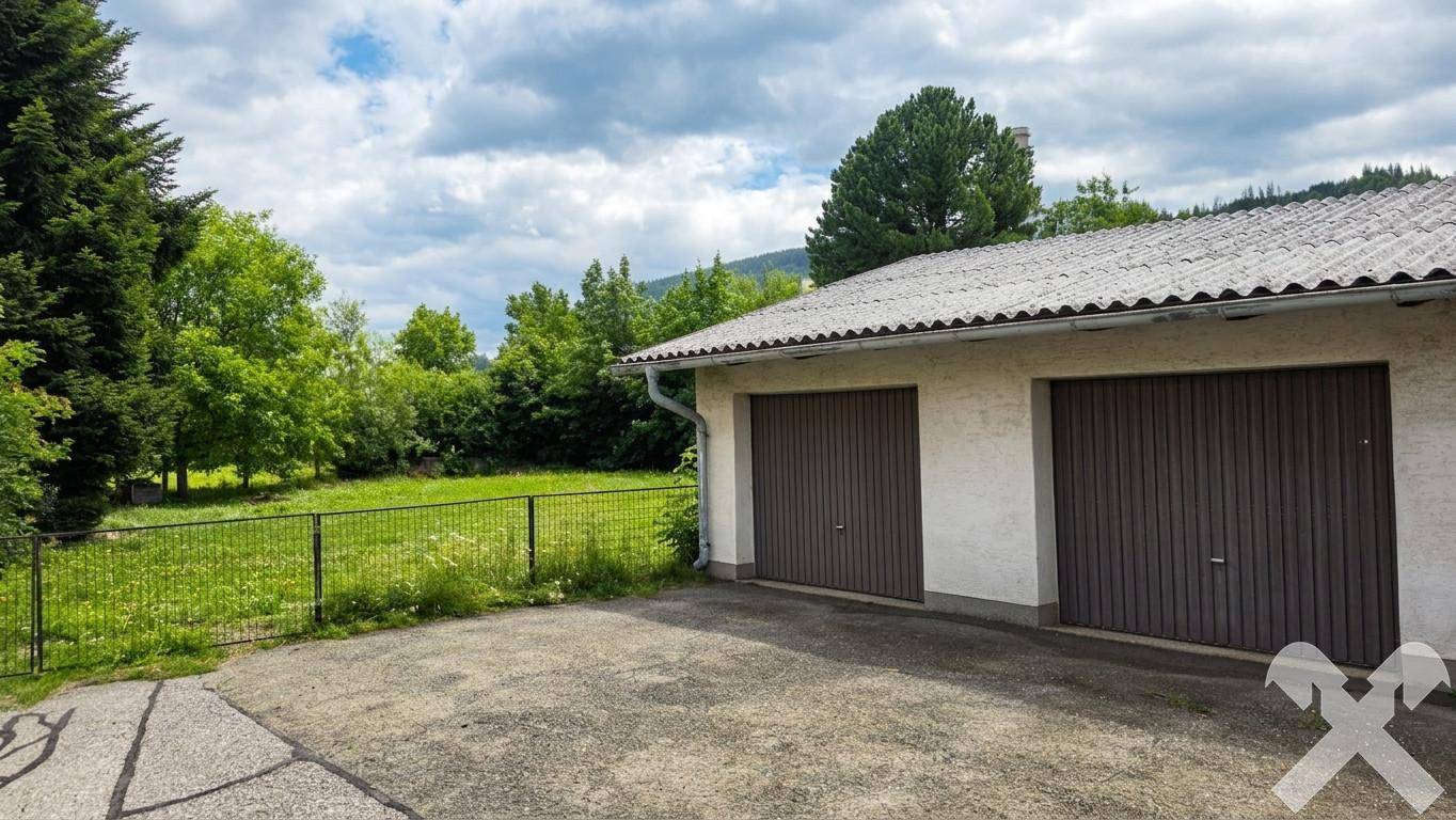 Doppelgarage mit braunen Toren und gepflasterter Zufahrt, umgeben von Grünflächen.