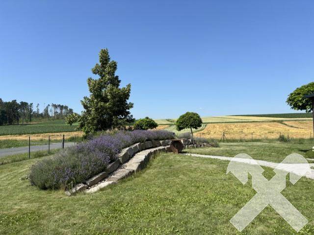 Gepflegter Gartenbereich mit Lavendelbeeten, Rasenflächen und weitem Blick über die Felder.