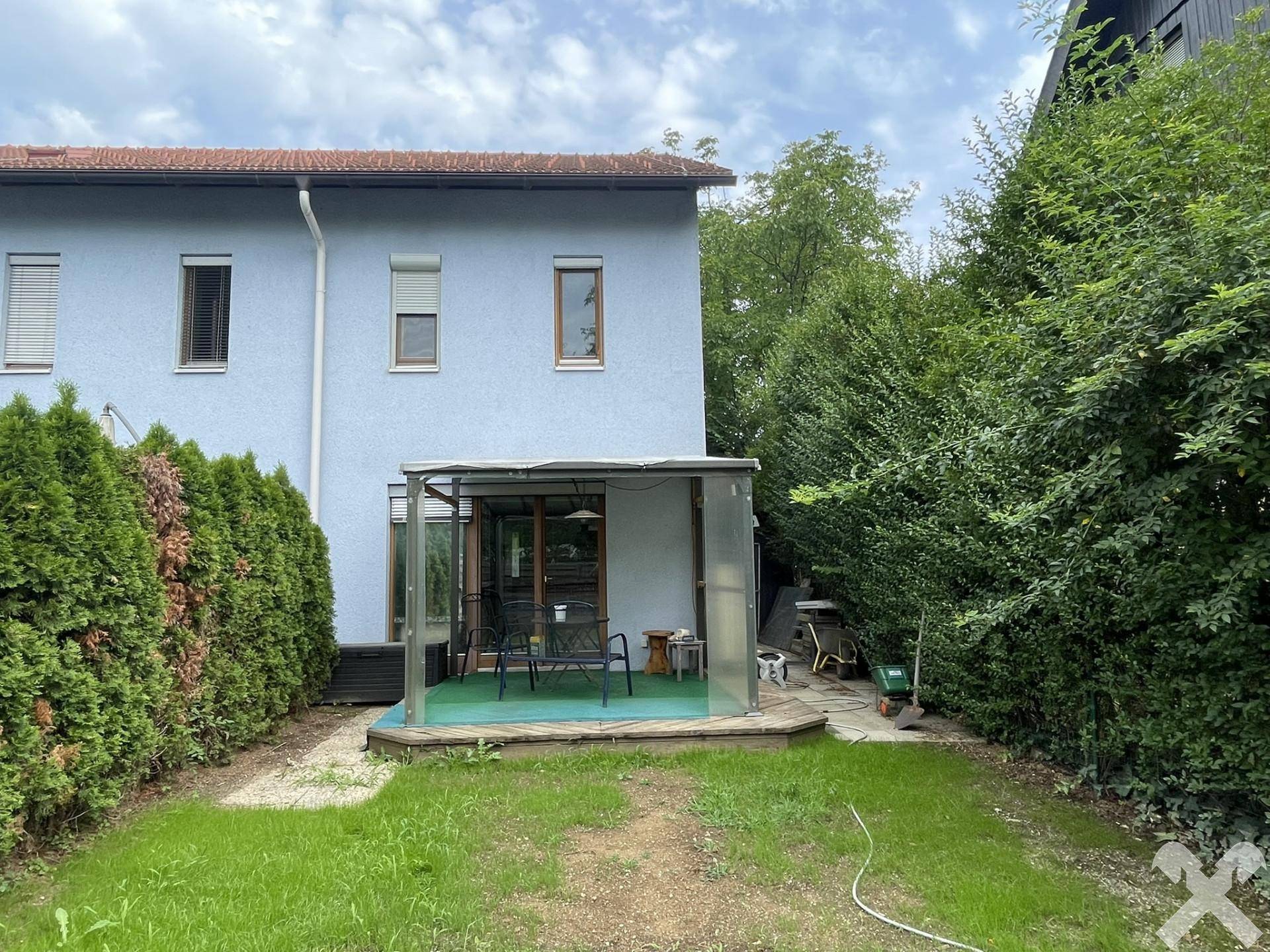 Überdachte Terrasse mit Gartenmöbeln und Blick auf den kleinen, umzäunten Garten.