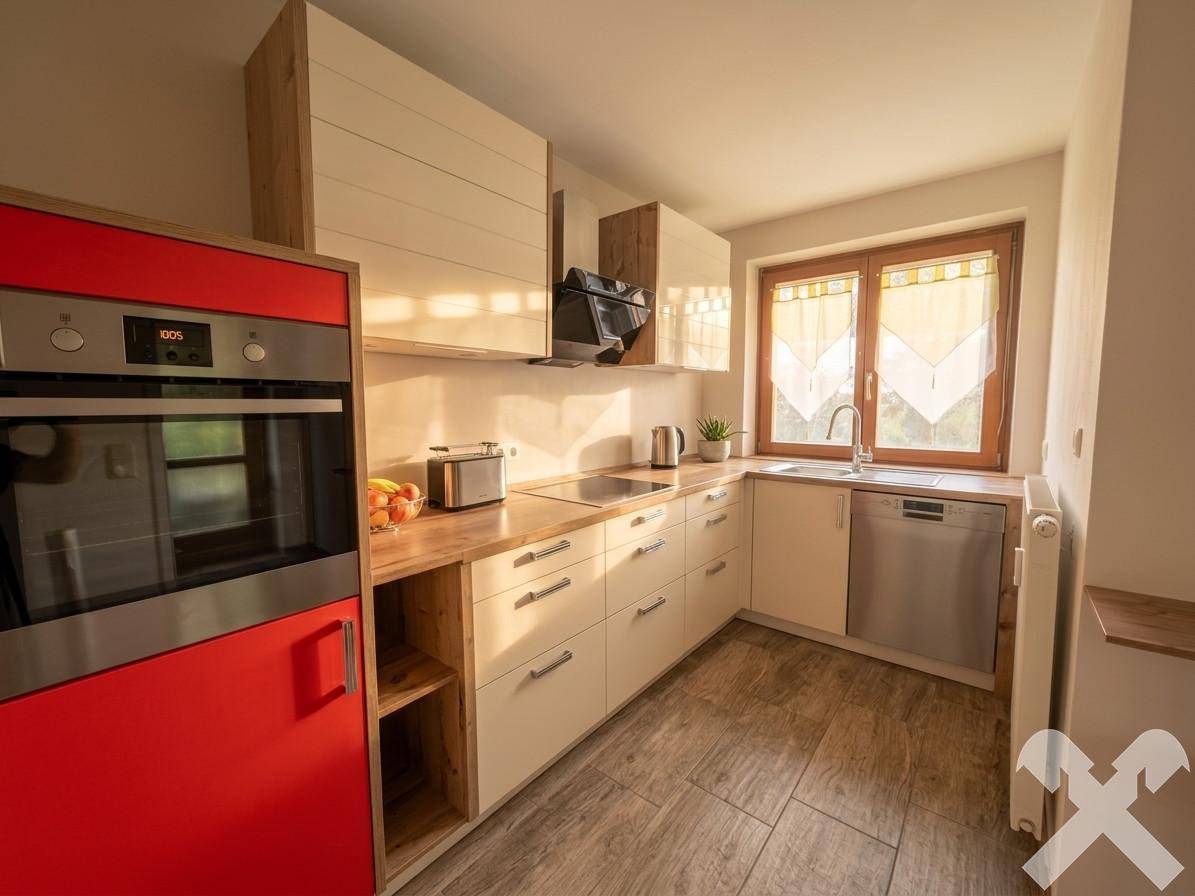 Moderne Einbauküche mit hellen Holzfronten, rotem Backofen und Fenster.