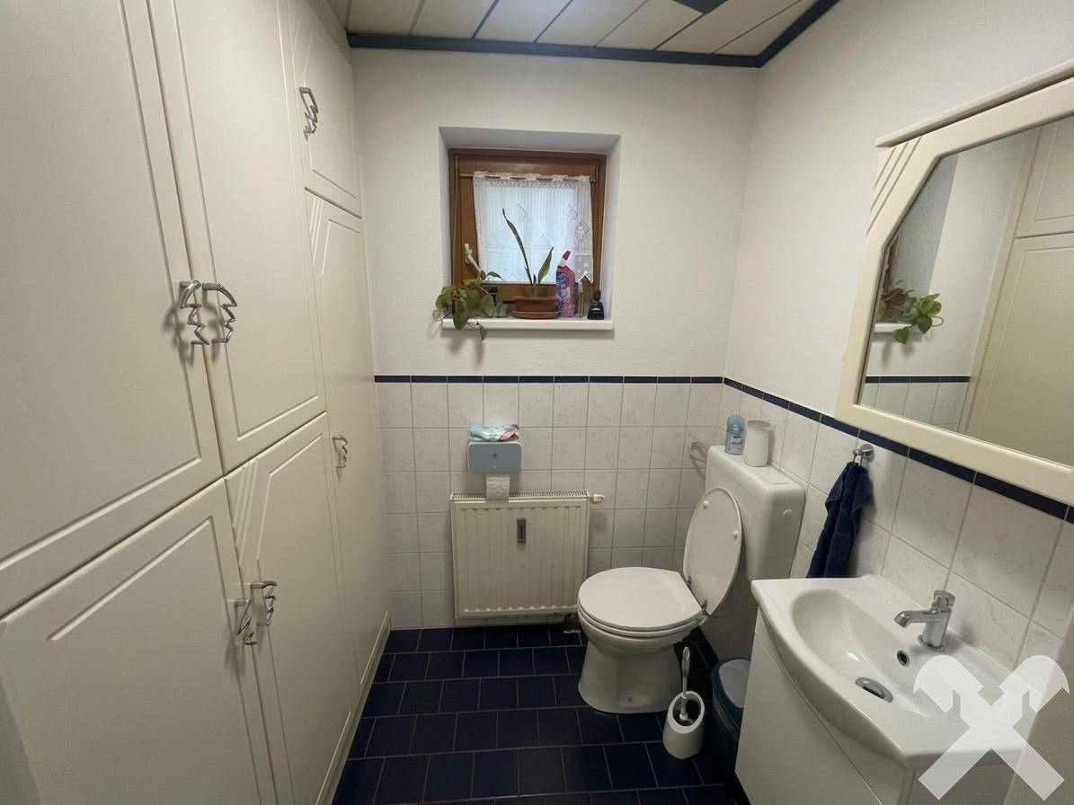 Kleines Gäste-WC mit Fenster, blauen Fliesen und praktischen Einbauschränken.