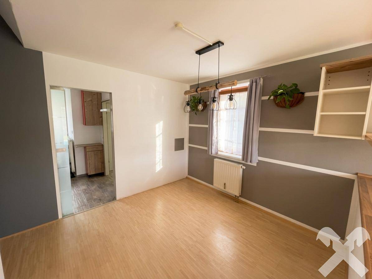 Essbereich mit Holzboden und modernem Hängelampen-Design, angrenzend an die Küche.