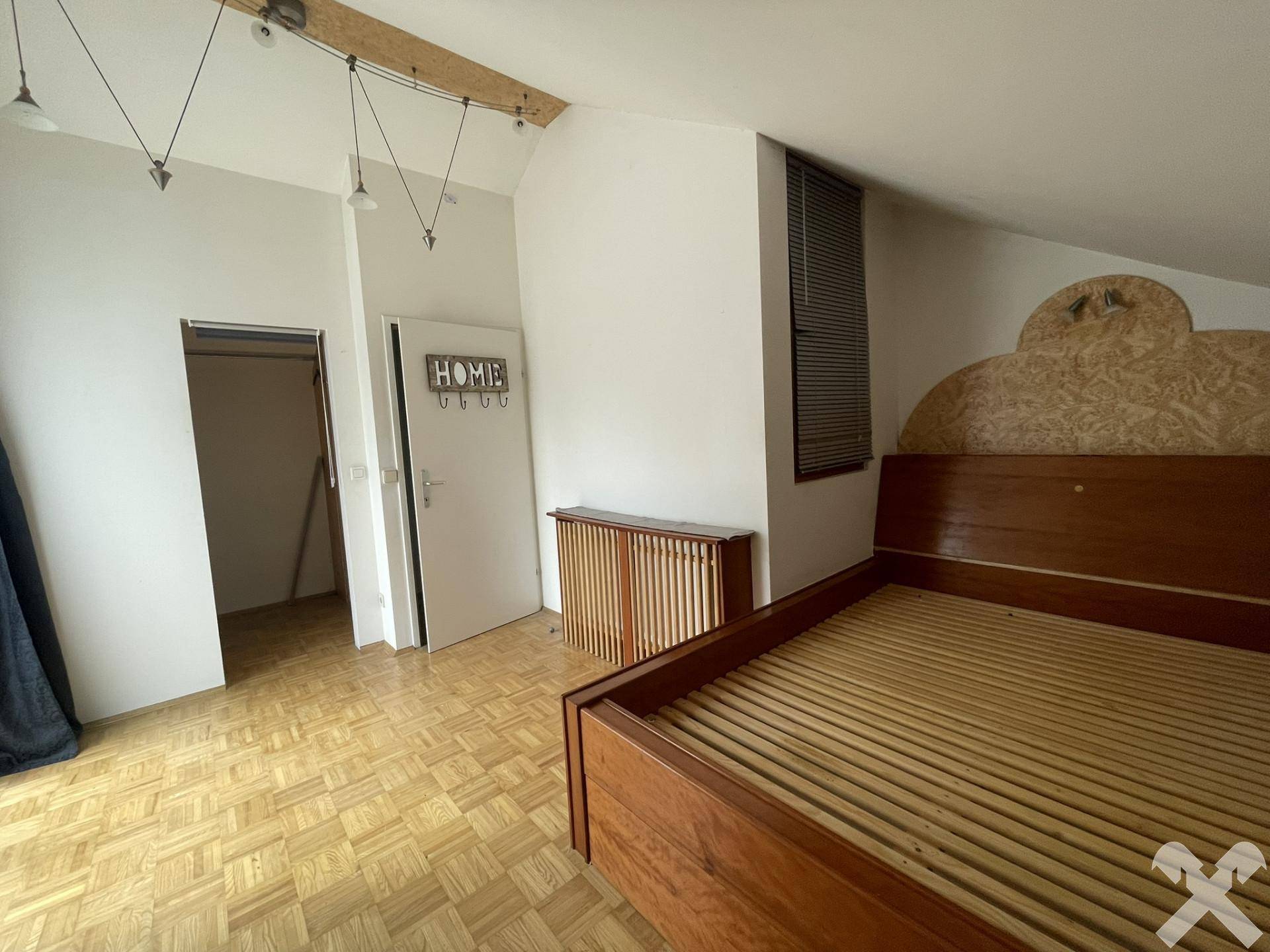 Gemütliches Schlafzimmer im Dachgeschoss mit Holzboden und schrägen Decken.