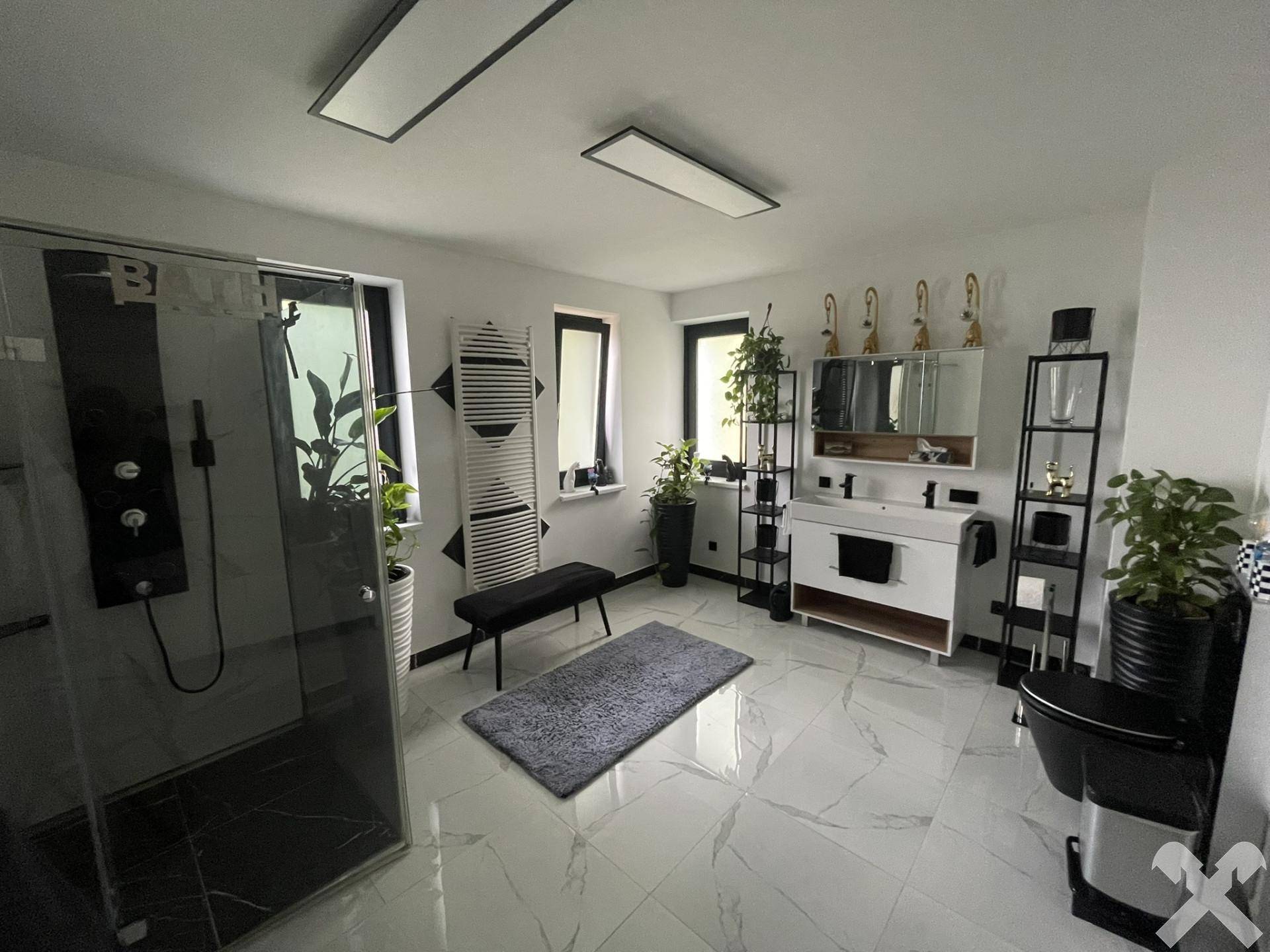 Modernes Badezimmer mit großen weißen Fliesen, begehbarer Dusche und Doppelwaschbecken.