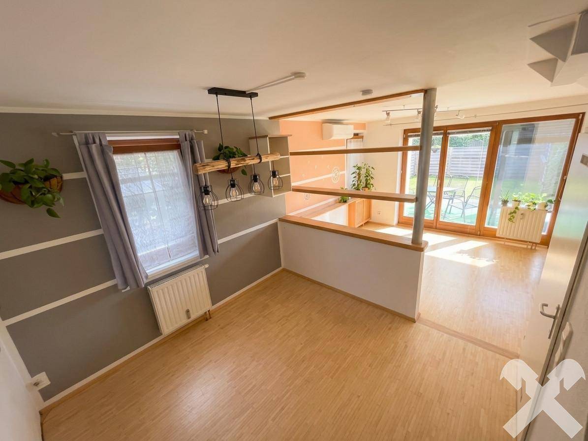 Offener Wohn- und Essbereich mit Holzboden, viel Tageslicht und Zugang zum Garten.