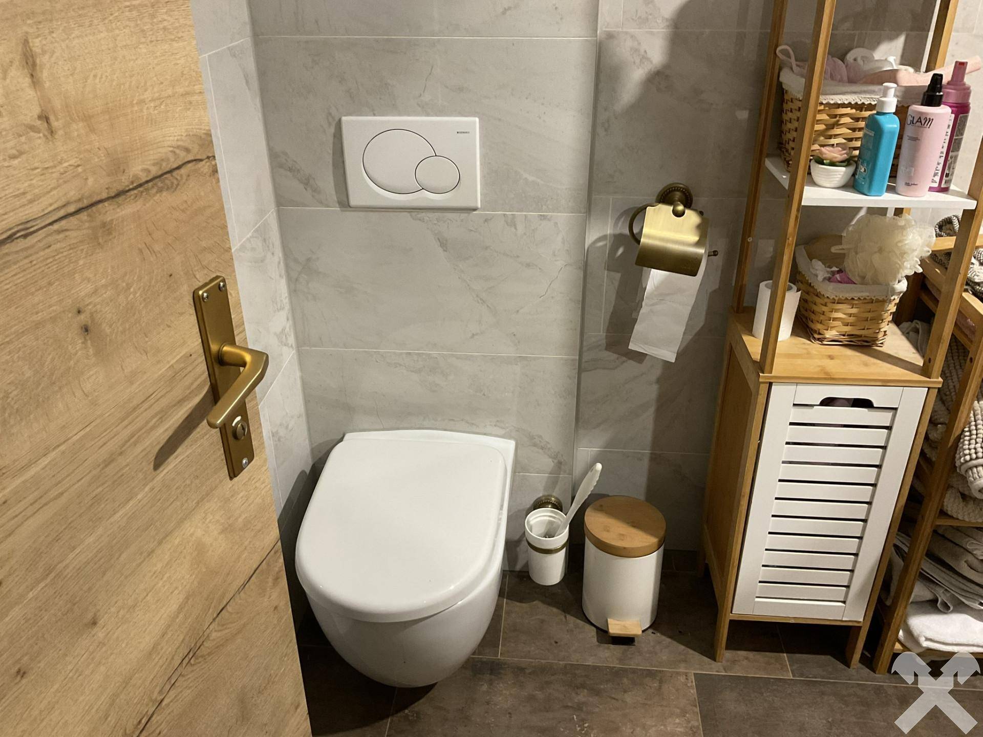 Modernes WC mit wandhängender Toilette und hellgrauen Fliesen, ergänzt durch ein Holzregal.