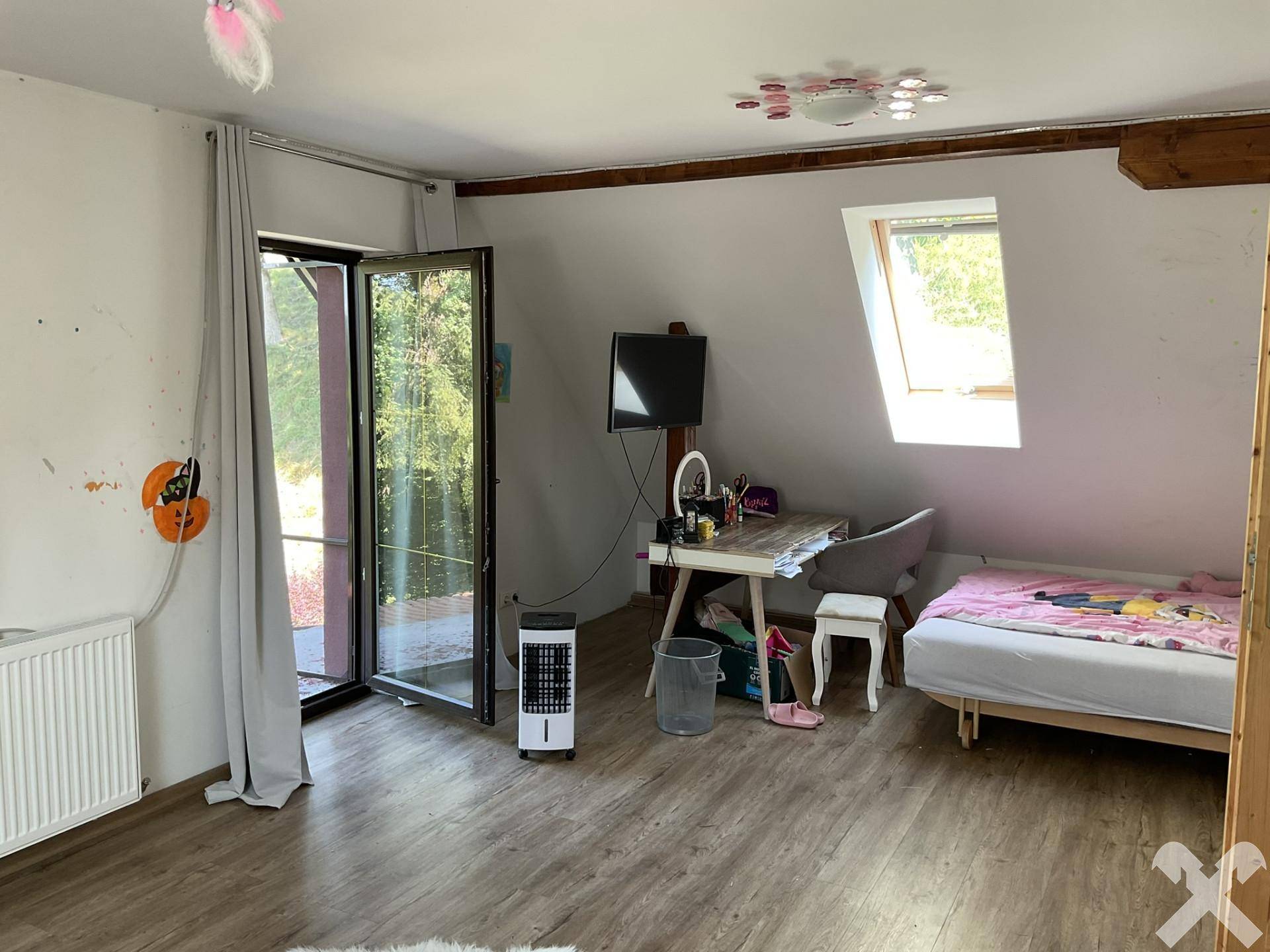 Kinderzimmer mit Bett, Schreibtisch und großem Zugang zu einem Außenbereich, inklusive Dachfenster.