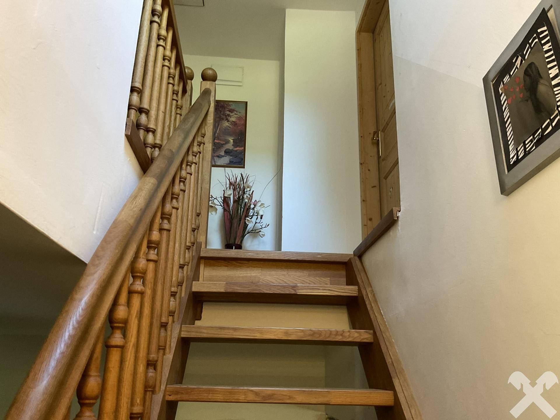 Holztreppe führt nach oben, umgeben von weißen Wänden und natürlichem Licht.