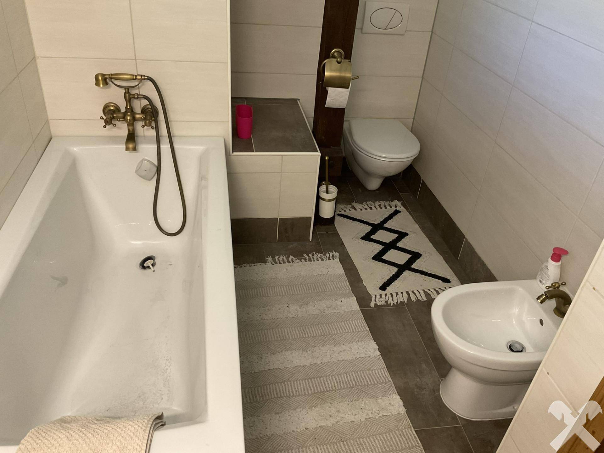 Badezimmer mit Badewanne, Toilette und Bidet, ausgestattet mit gefliestem Boden und Wänden.