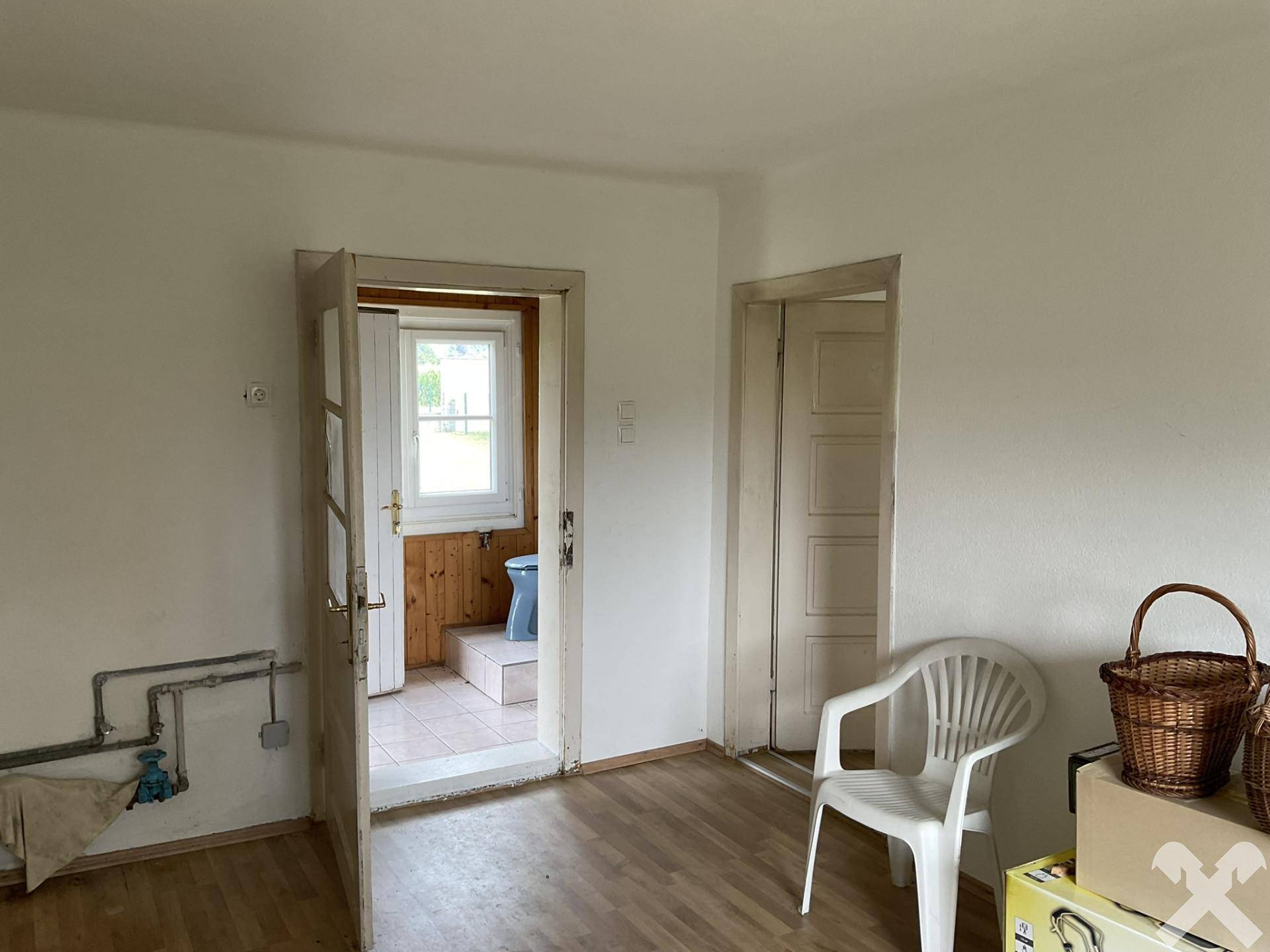 Flur mit Laminatboden und Türen zu angrenzenden Räumen, inklusive Blick in ein kleines Badezimmer.