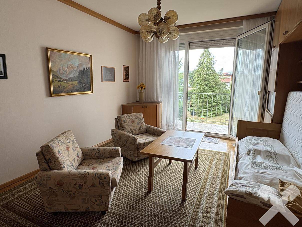 Helles Wohnzimmer mit traditionellen Möbeln, Parkettboden und Blick ins Grüne vom Balkon.
