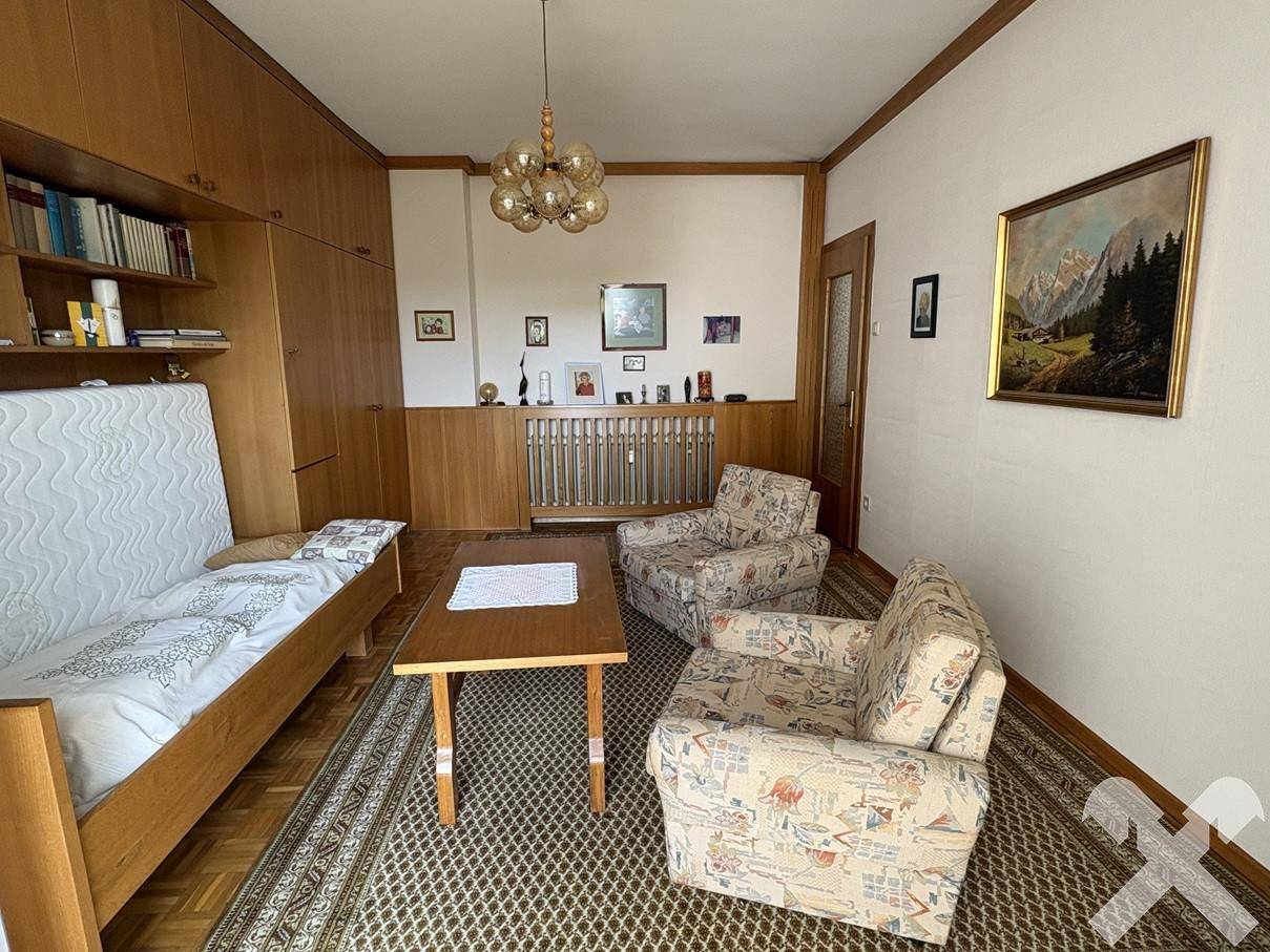 Wohnzimmer mit Holzvertäfelung, Teppich und integriertem Bett in einer Schrankwand.