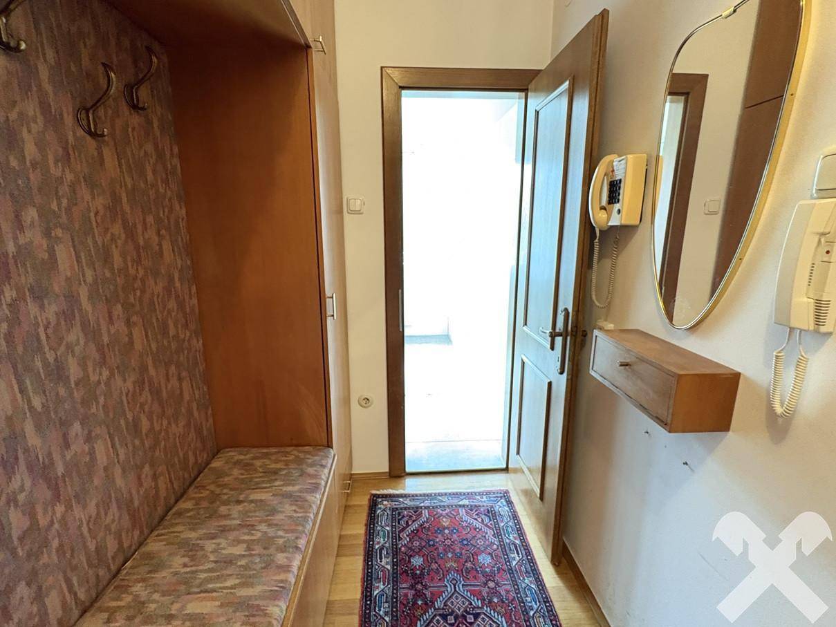 Eingangsbereich mit Garderobe, Spiegel und Gegensprechanlage, einladend gestaltet.