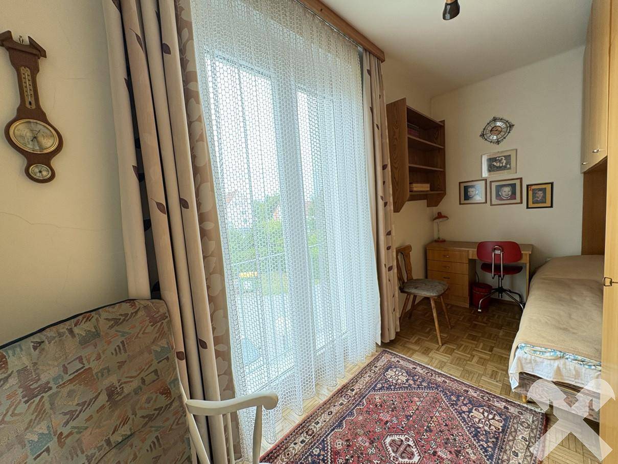 Schlafzimmer mit Einzelbett, Schreibtisch und Zugang zu einem kleinen Balkon.