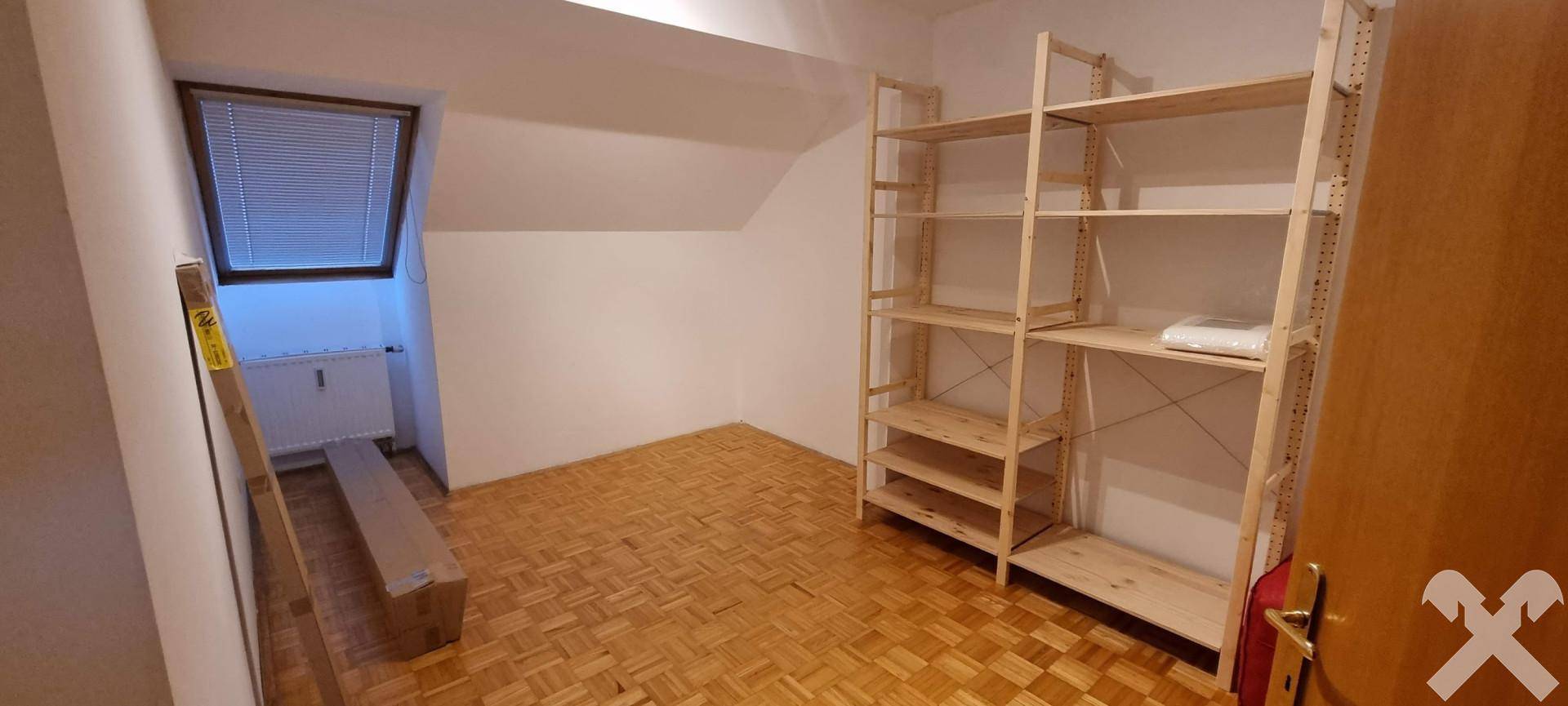Praktischer Abstellraum mit Parkettboden, Dachschräge und Holzregalen für zusätzlichen Stauraum.