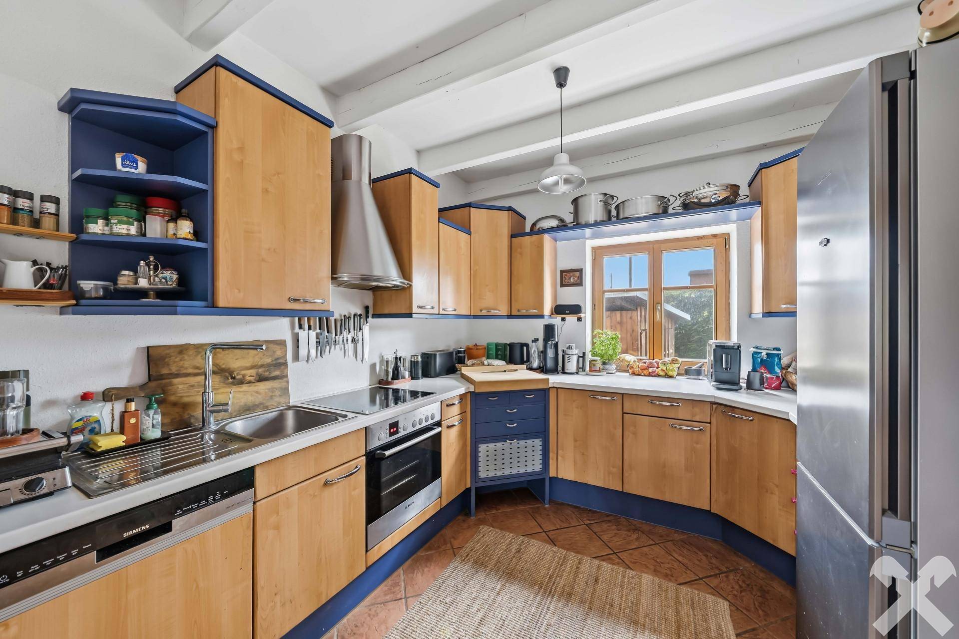 Rustikale Küche mit Holzschränken, blauen Akzenten und modernen Einbaugeräten.