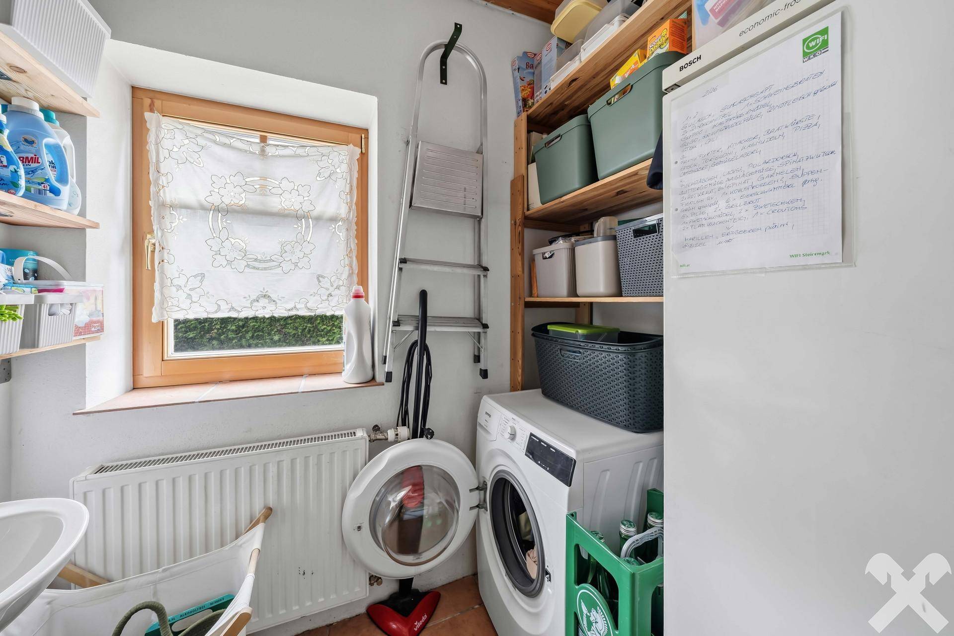 Praktischer Hauswirtschaftsraum mit Waschmaschine, Trockner und Regalen für Lagerung.