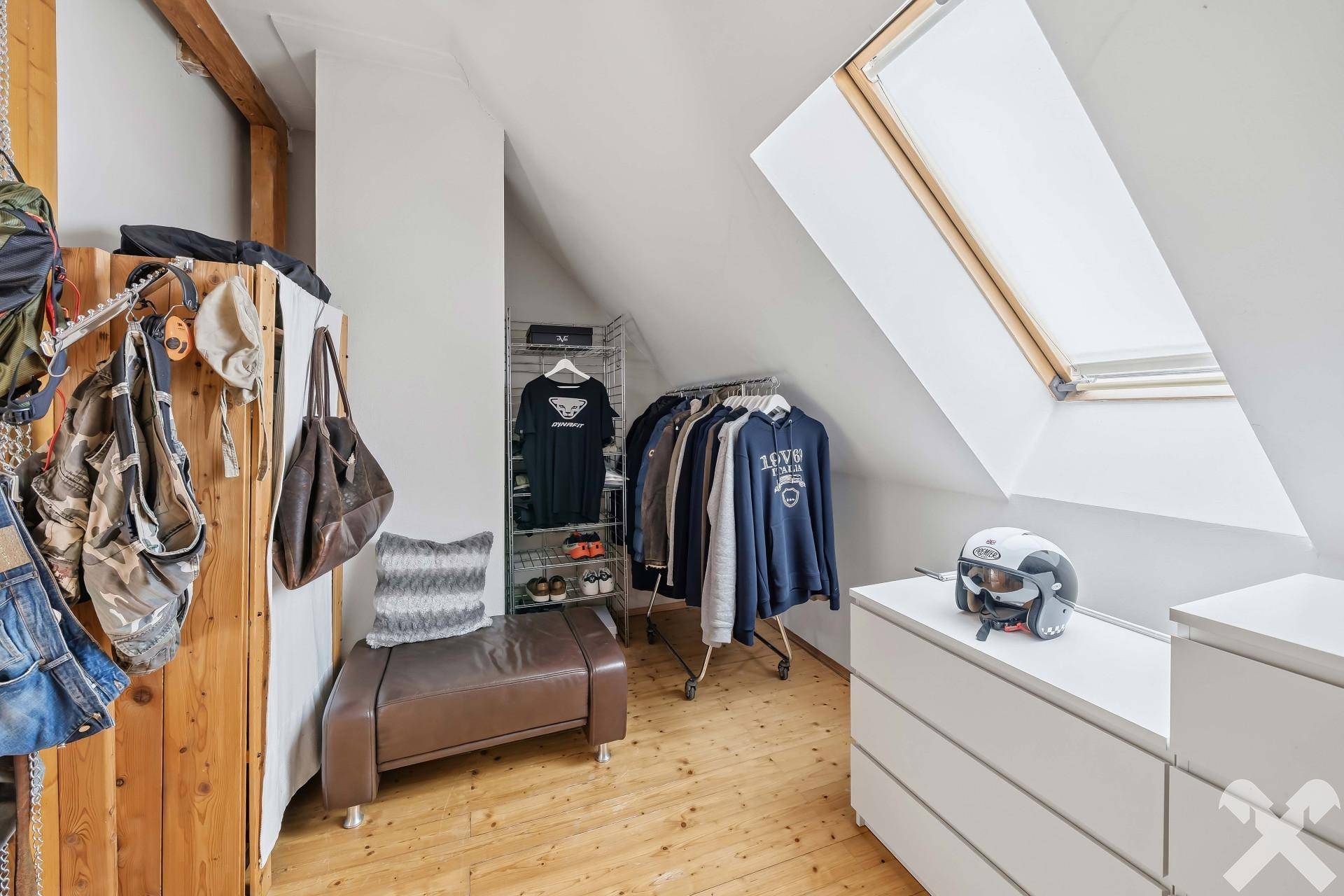 Praktischer begehbarer Kleiderschrank im Dachgeschoss mit Dachfenster und Stauraum.
