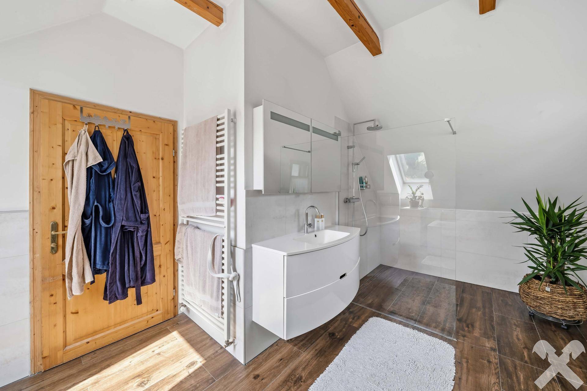 Modernes Badezimmer mit begehbarer Dusche, Waschbecken und beheiztem Handtuchhalter.