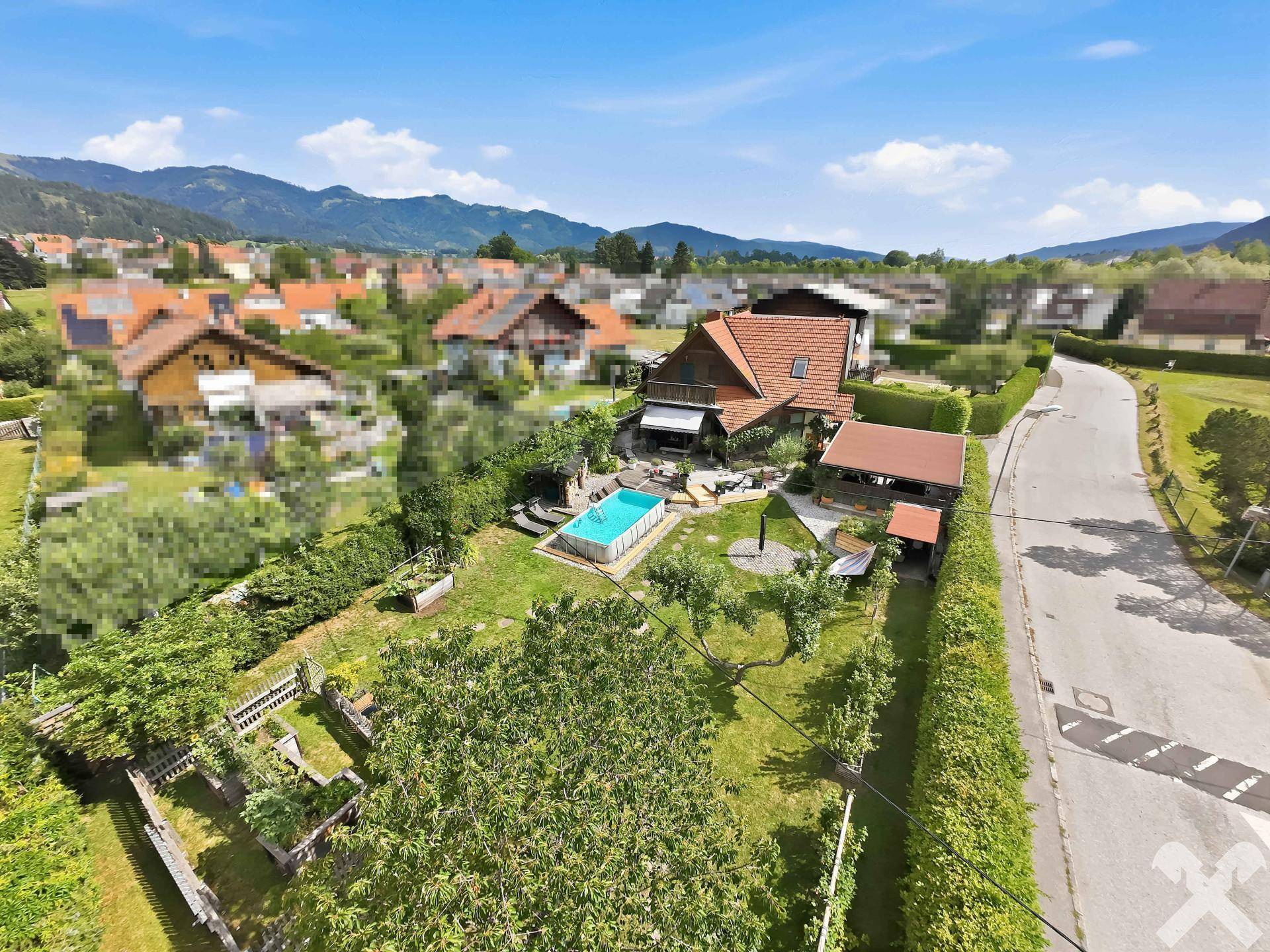 Panoramablick aus der Luft auf das Wohnhaus mit großem Garten, Pool und der malerischen Berglandschaft.